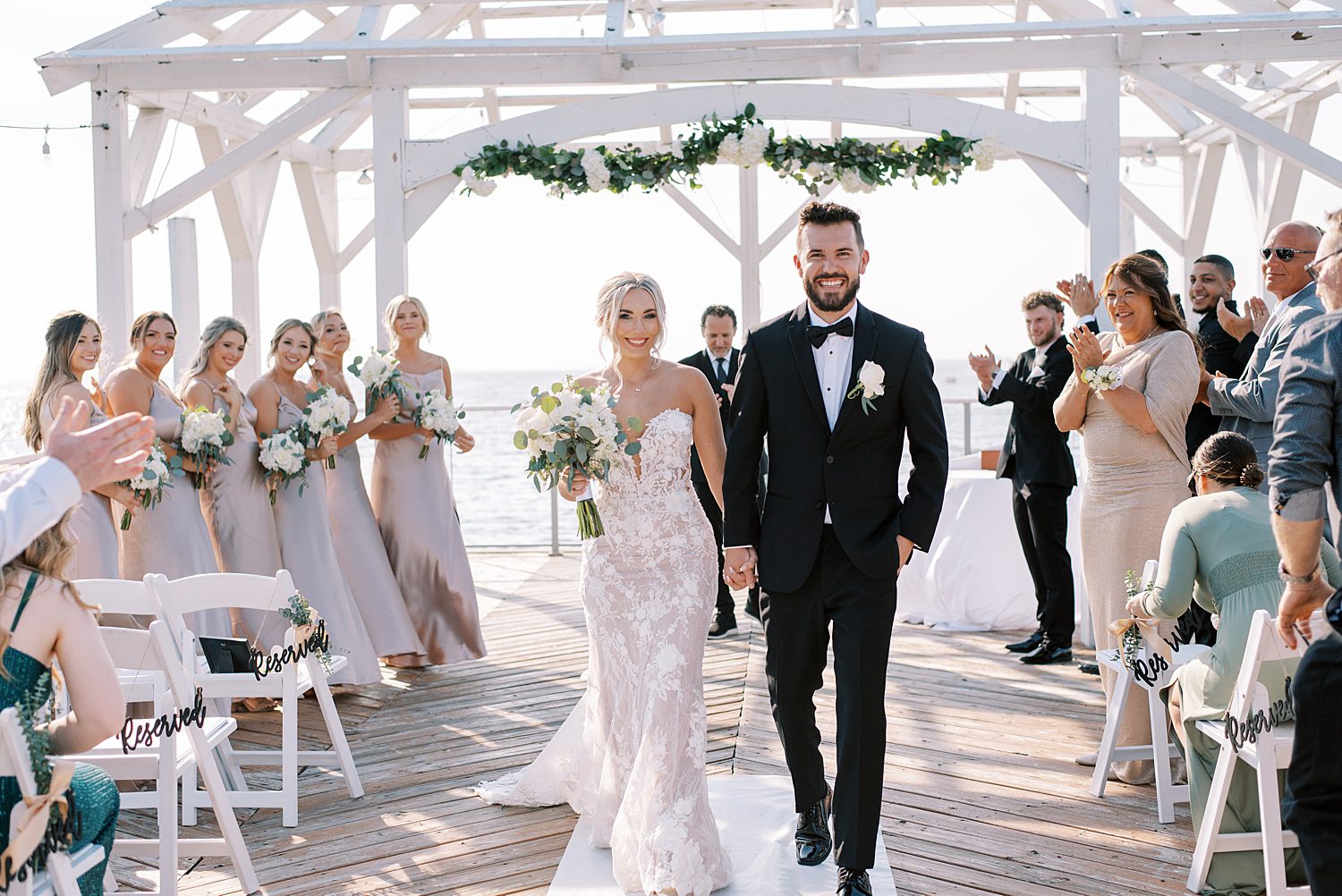 bride and groom walk down aisle outside white wood gazebo at The Godfrey Hotel