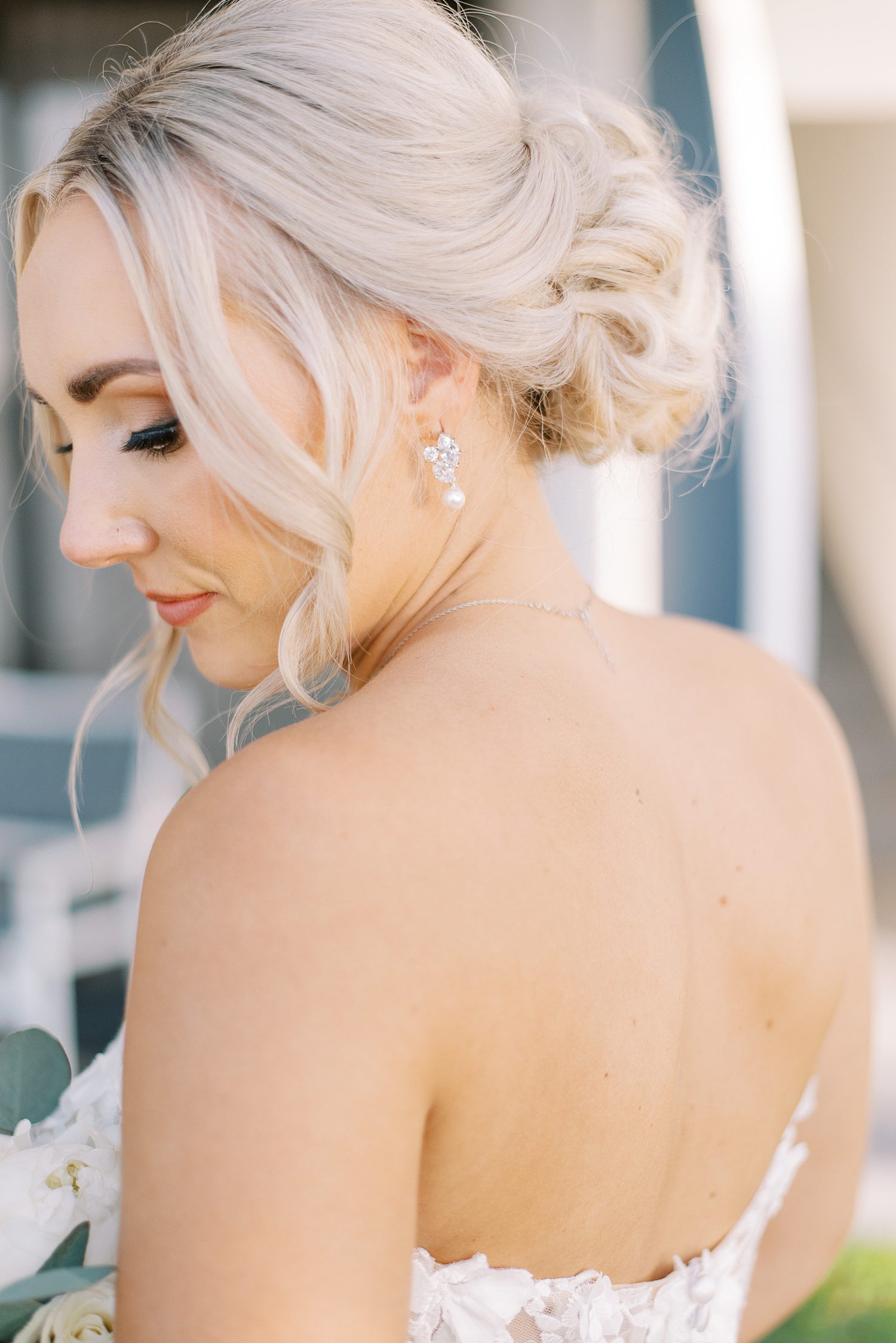 blonde woman in strapless wedding gown looks over shoulder with hair in bun