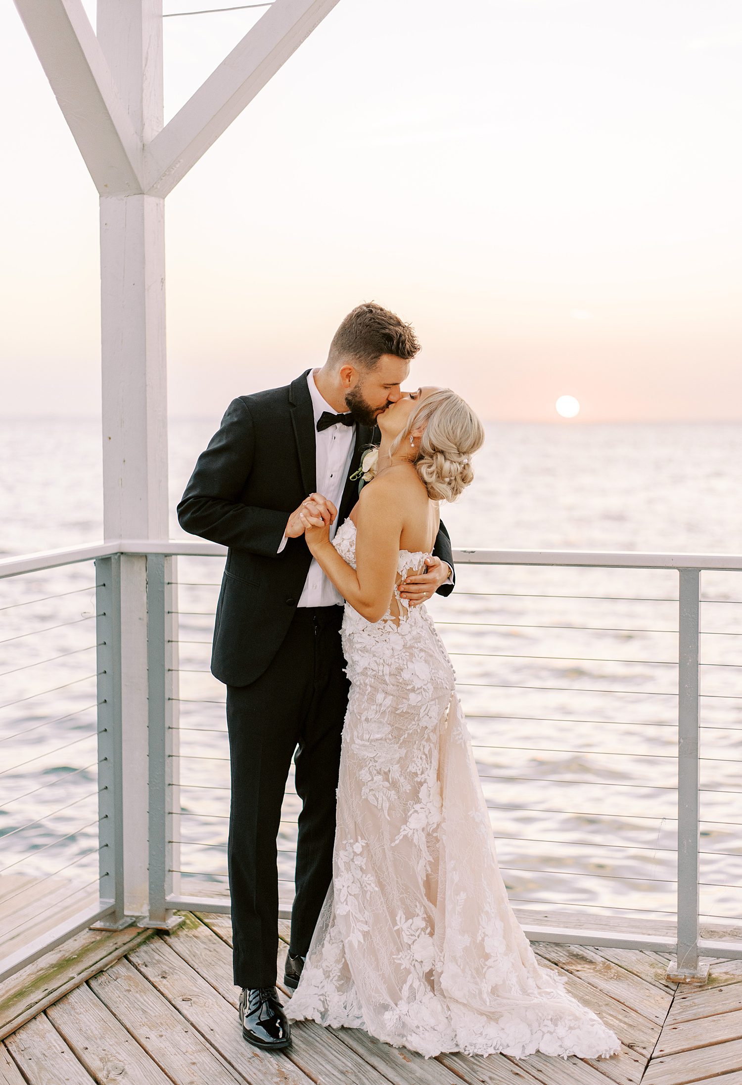 bride and groom kiss at sunset in corner of wooden dock at The Godfrey