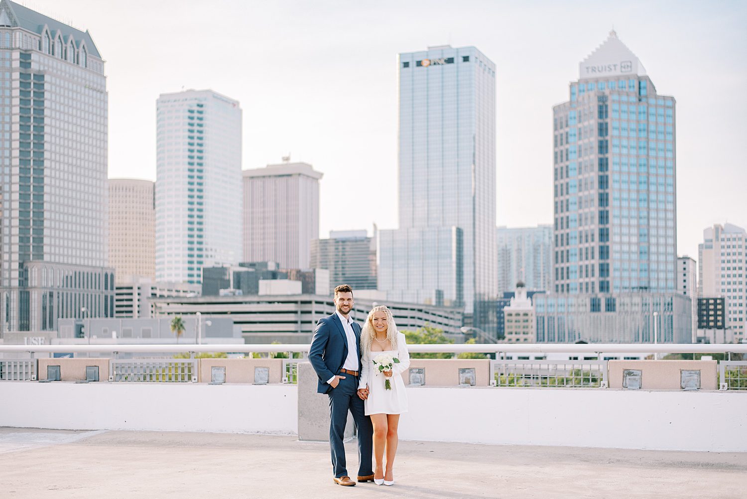 bride and groom stand together against railing on downtown Tampa rooftop