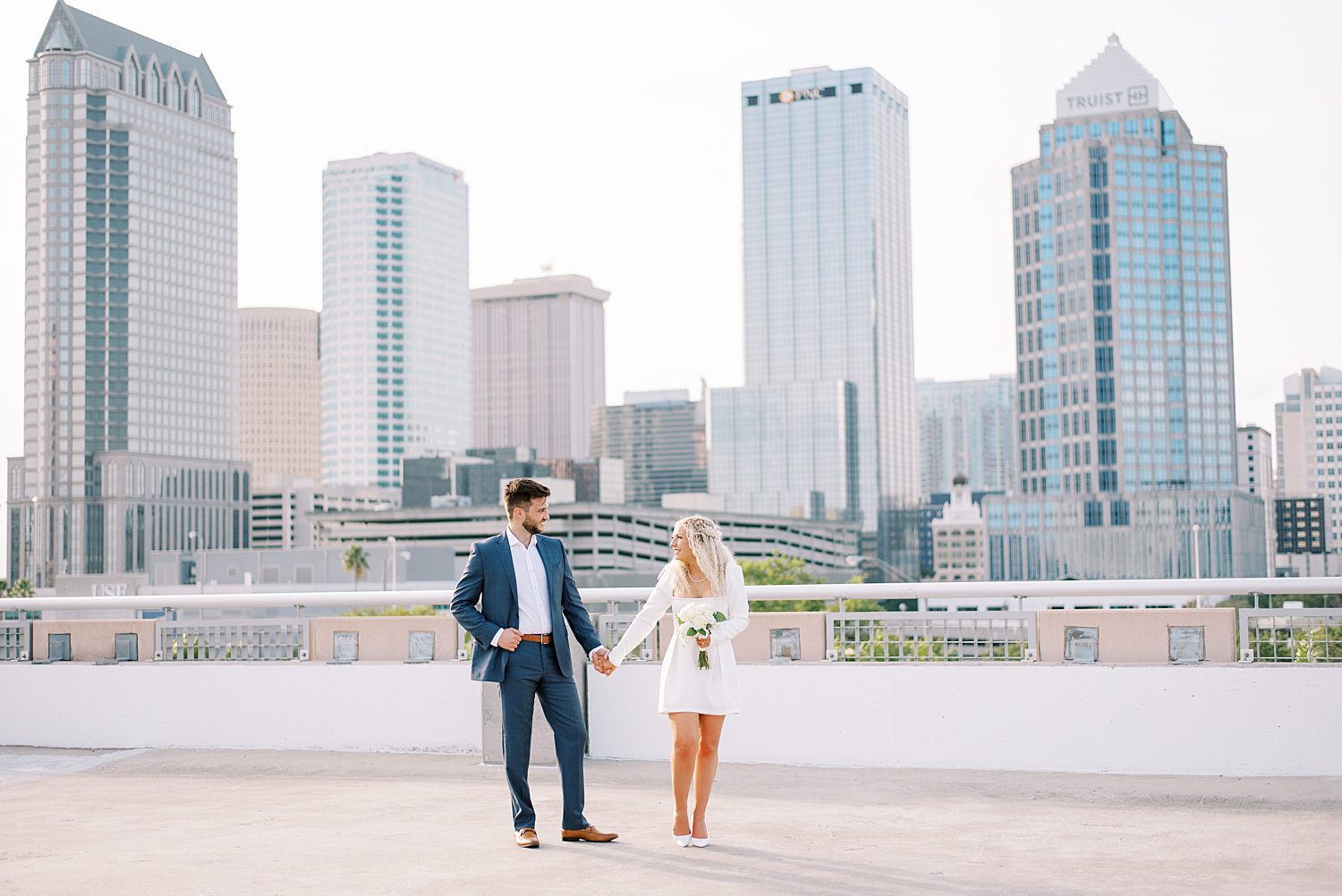 engaged couple holds hands walking on downtown Tampa rooftop