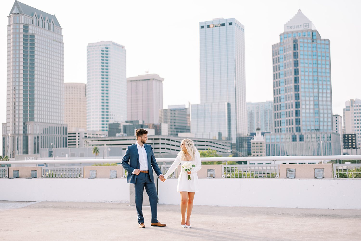 engaged couple holds hands walking on downtown Tampa rooftop