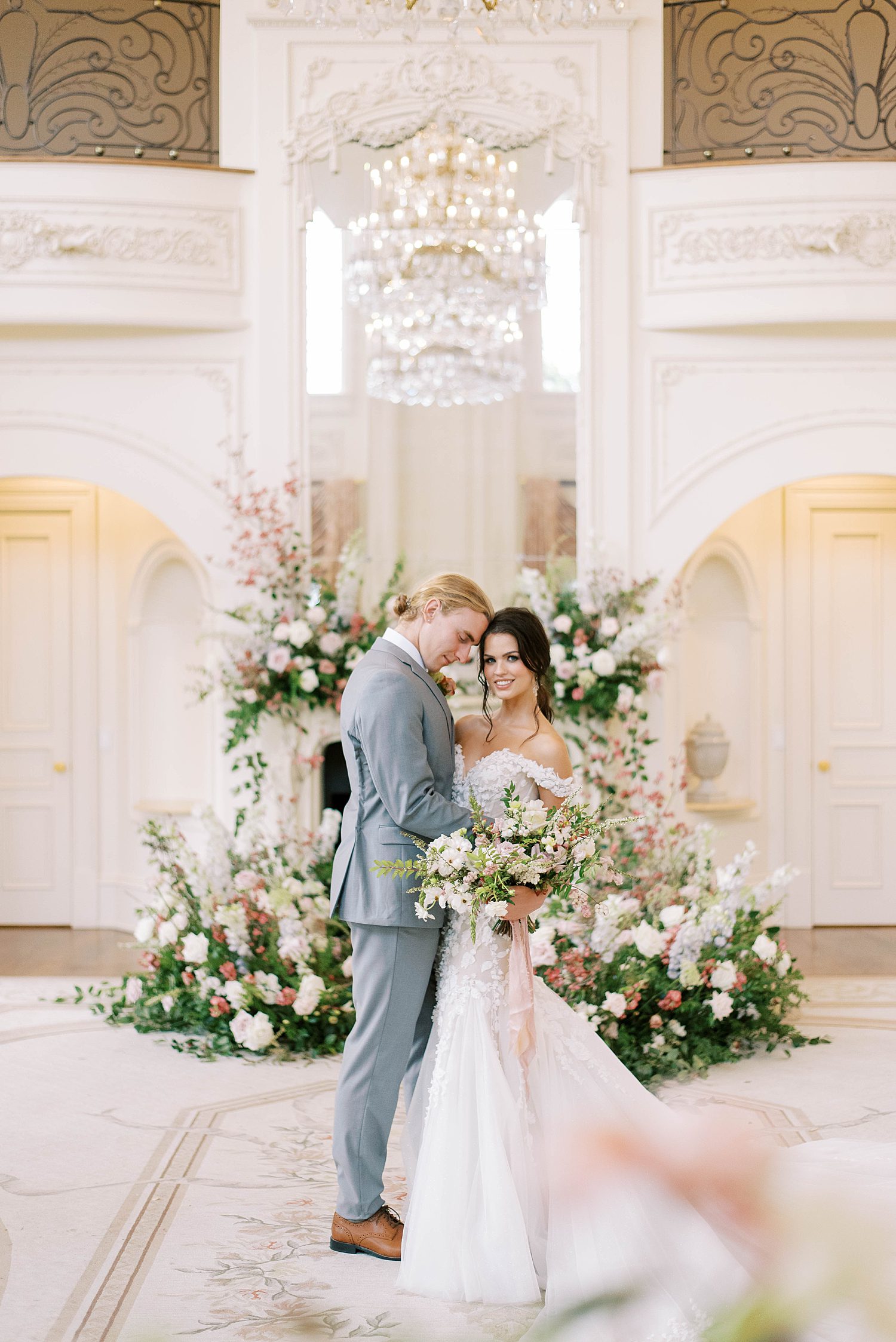 bride and groom hug by floral arrangement inside the Olana 