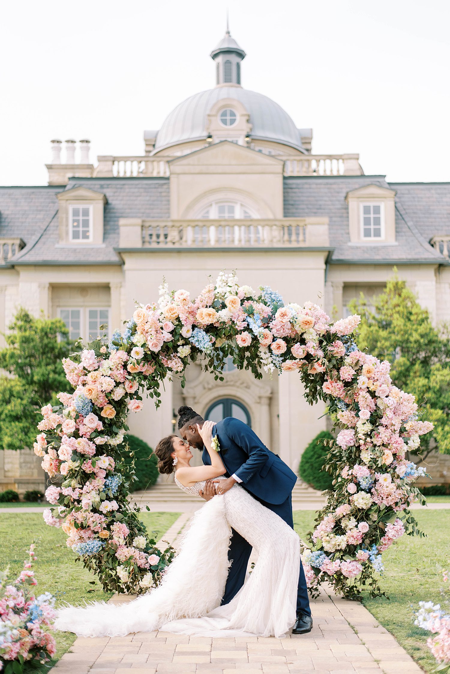 man dips woman under floral arbor outside The Olana