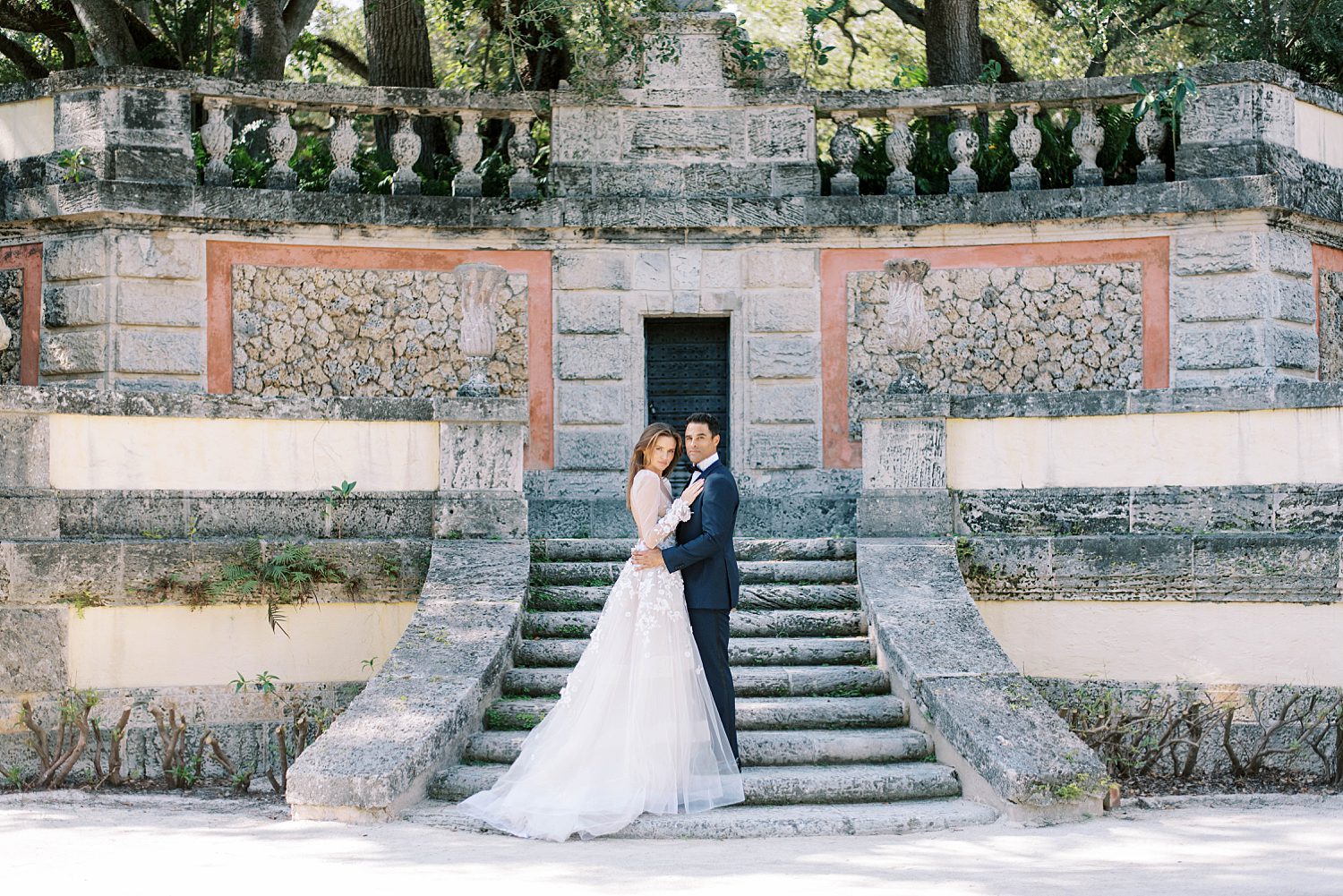 bride and groom hug on stone steps at Vizcaya Museum