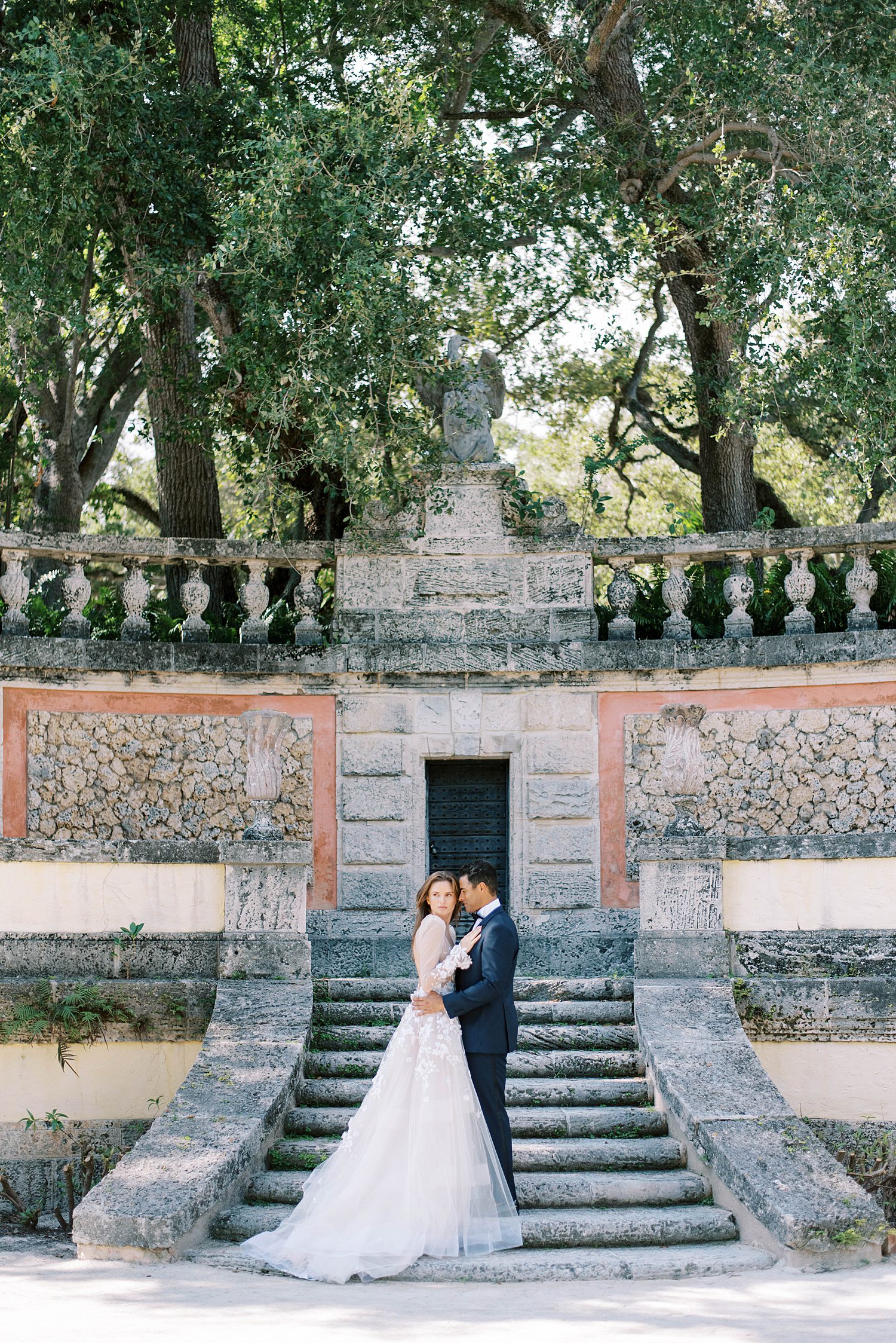 newlyweds stand on stone steps at Vizcaya Museum