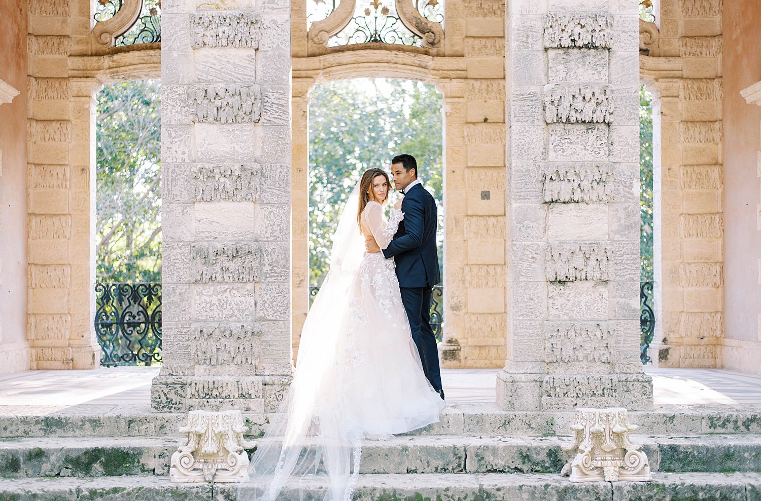 bride and groom stand in stone arbor at Vizcaya Museum