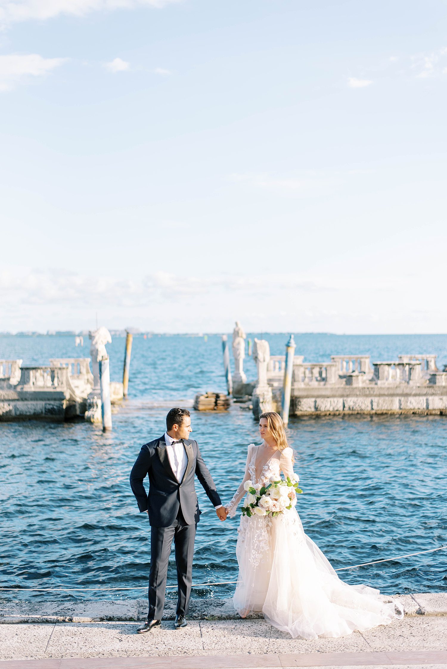 bride and groom hold hands by Miami Beach waterfront