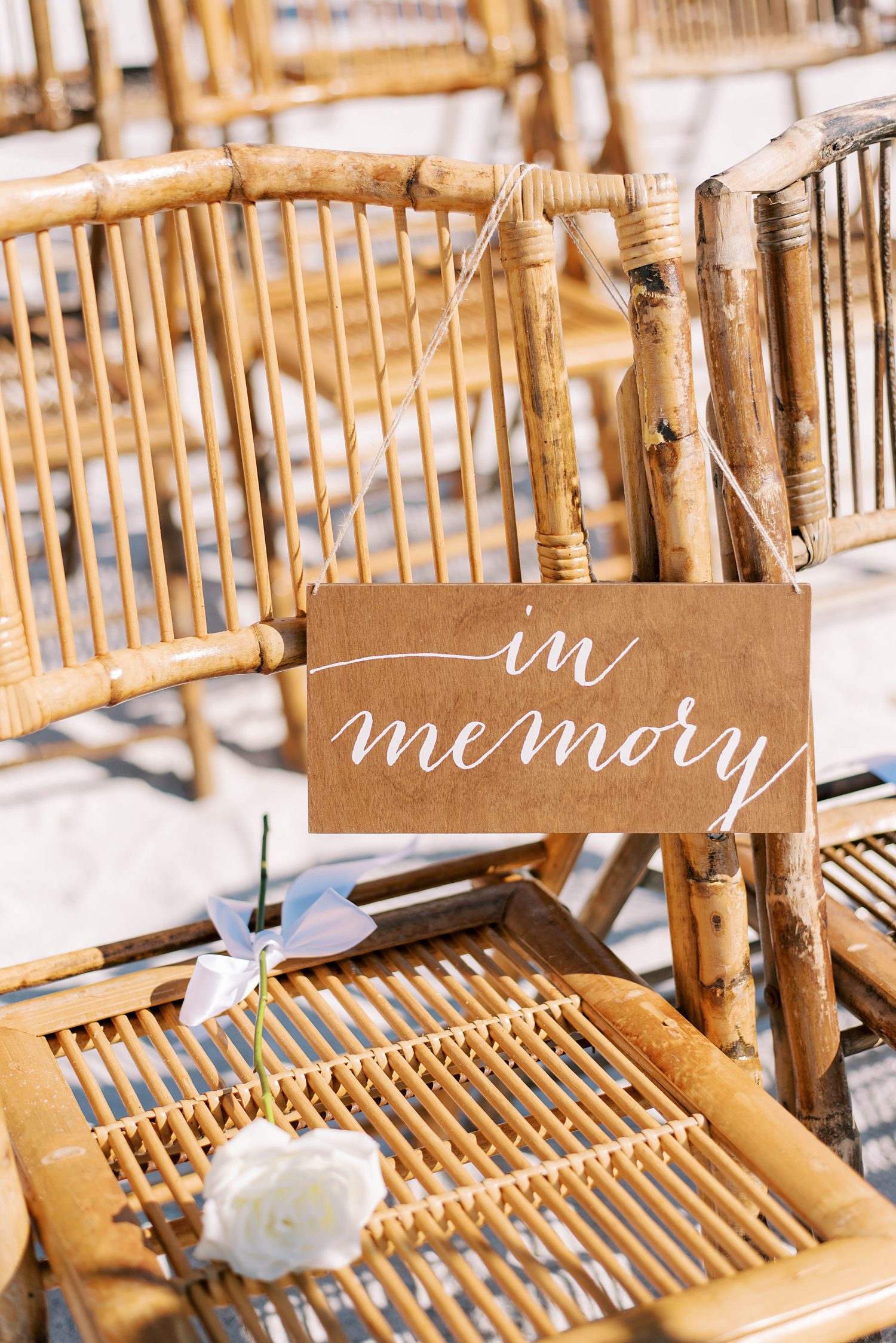 in memory sign with white rose on rattan chairs 