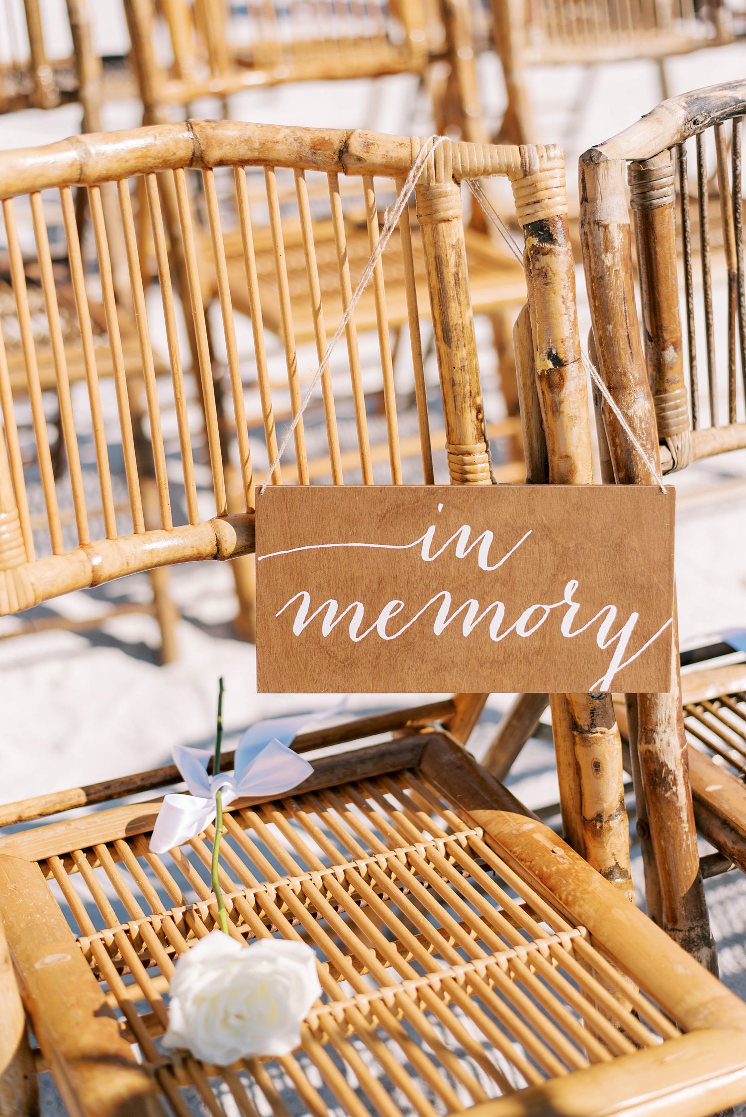in memory sign with white rose on rattan chairs