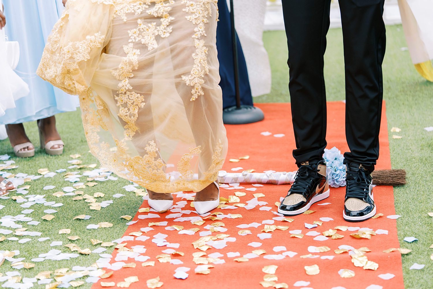 bride and groom jump over broom on red 