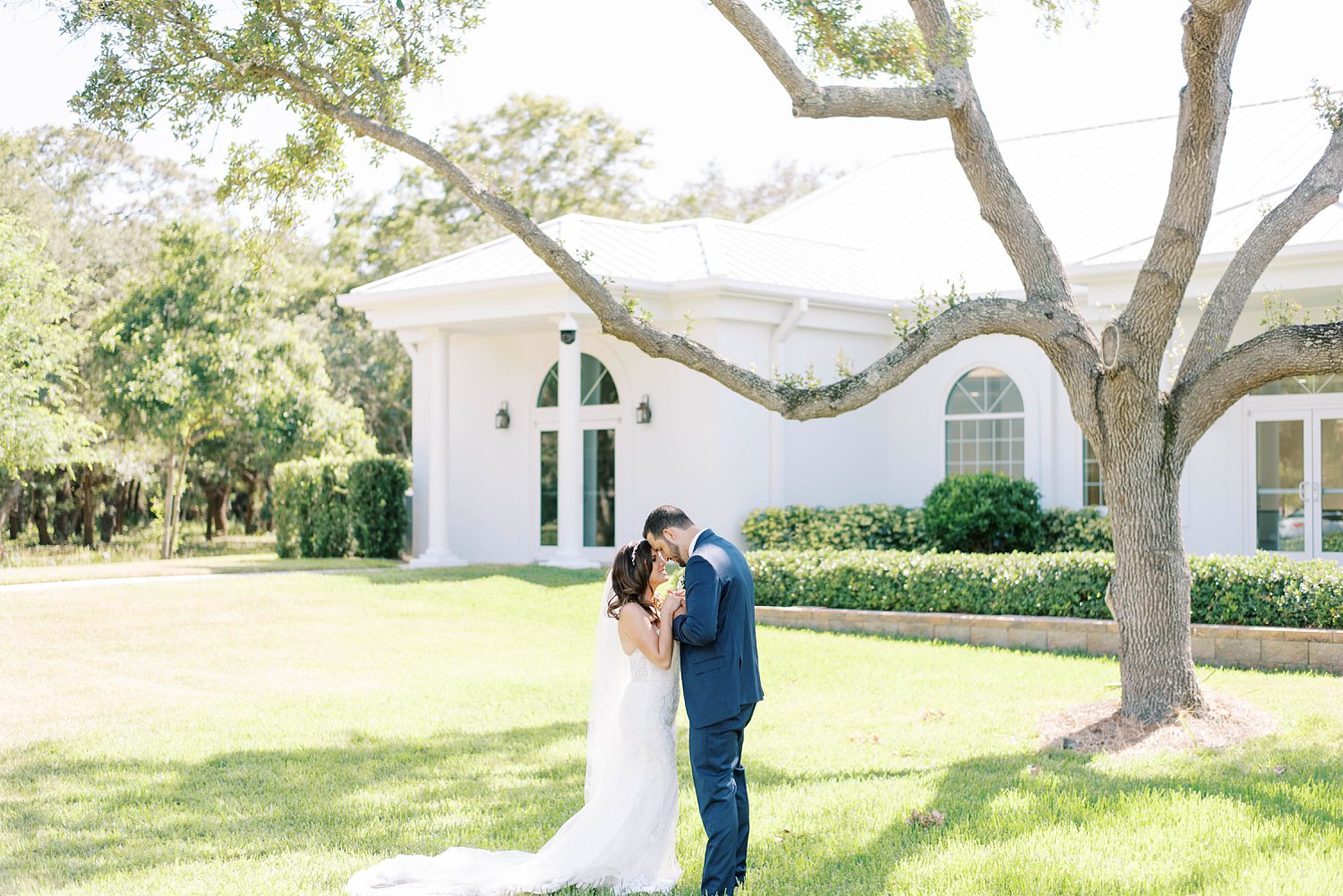 bride and groom kiss under tree outside Harborside Chapel