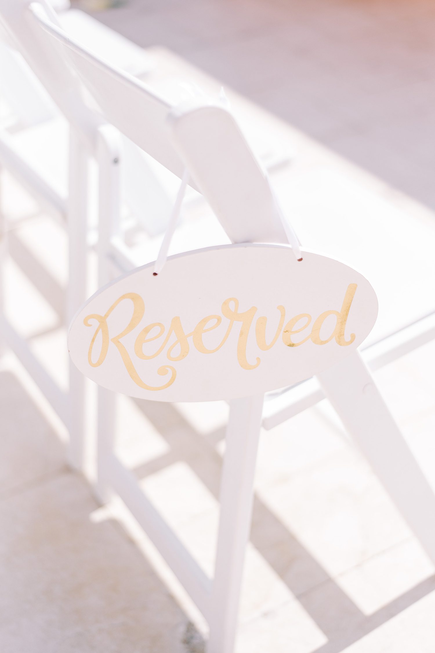 gold and white reserved sign on chair for wedding ceremony 