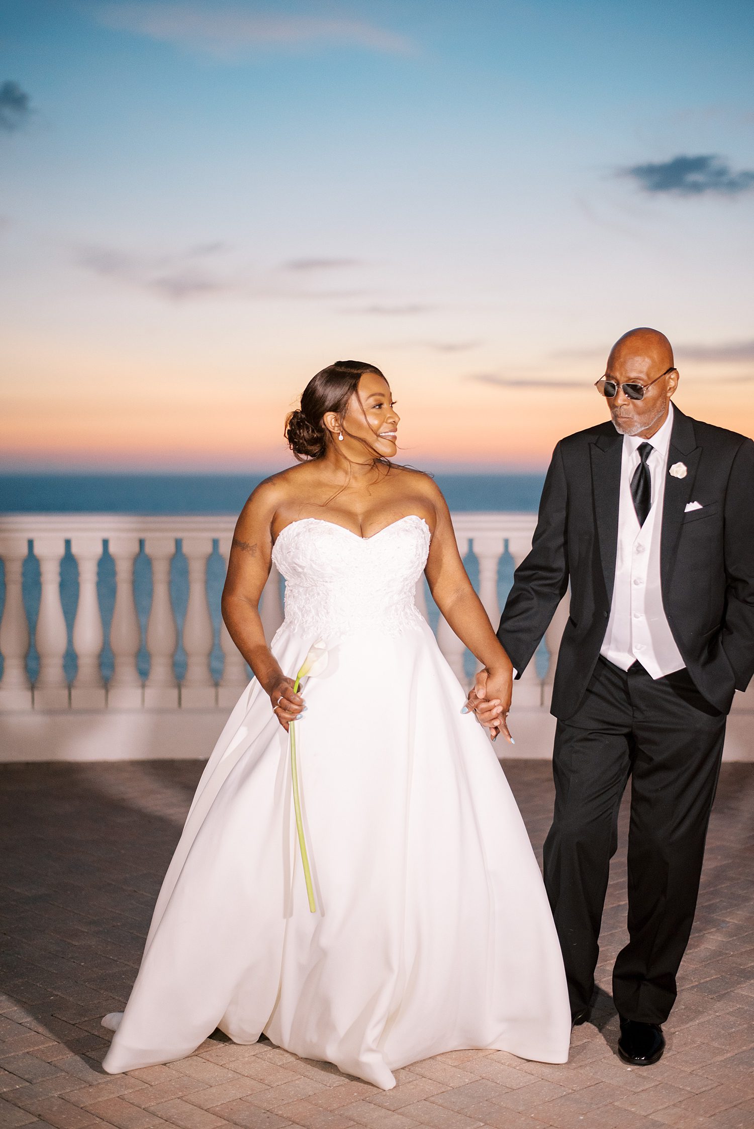 bride and groom hold hands walking on patio at the Hyatt Clearwater at sunset 