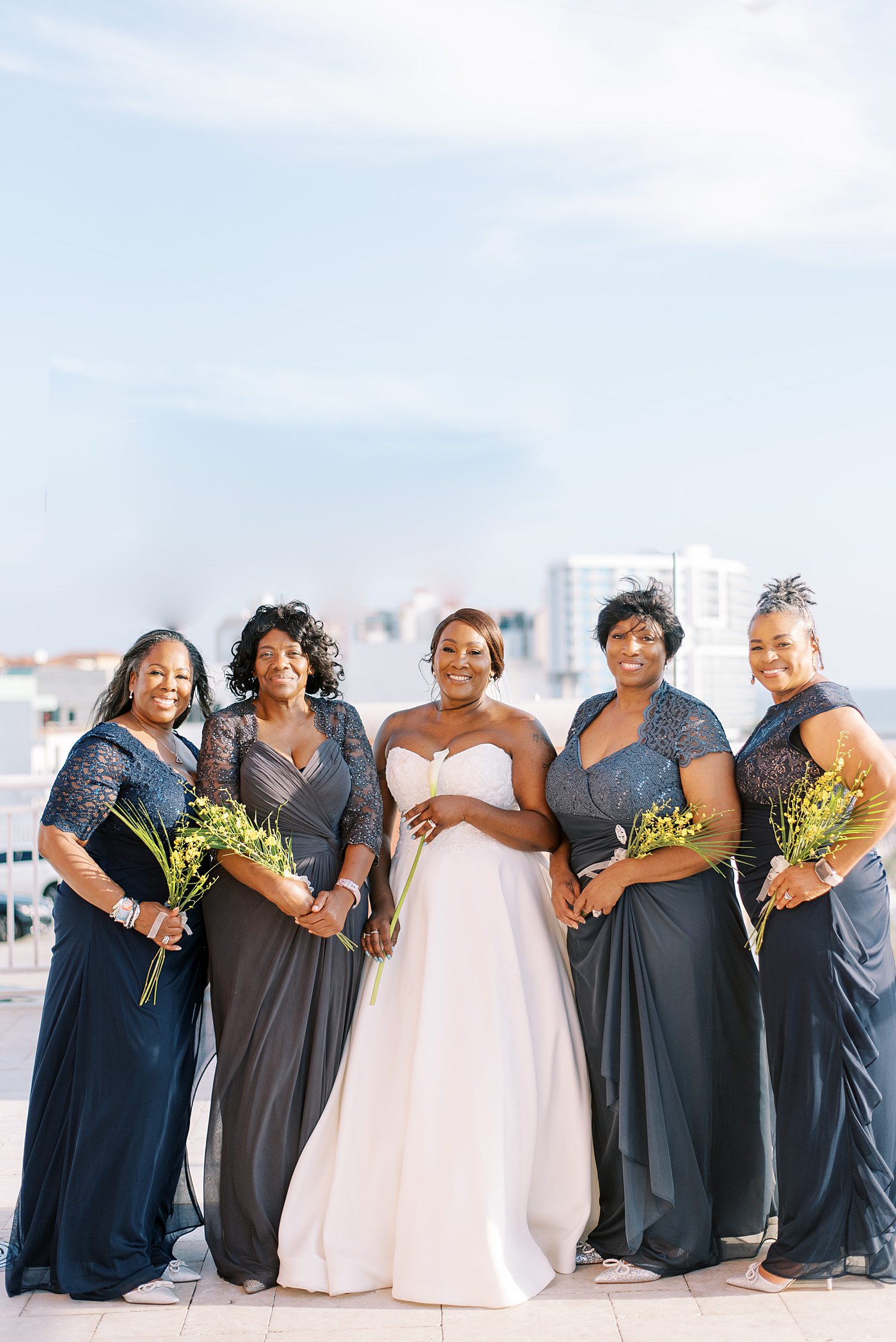 bride poses with bridesmaids in grey dresses 