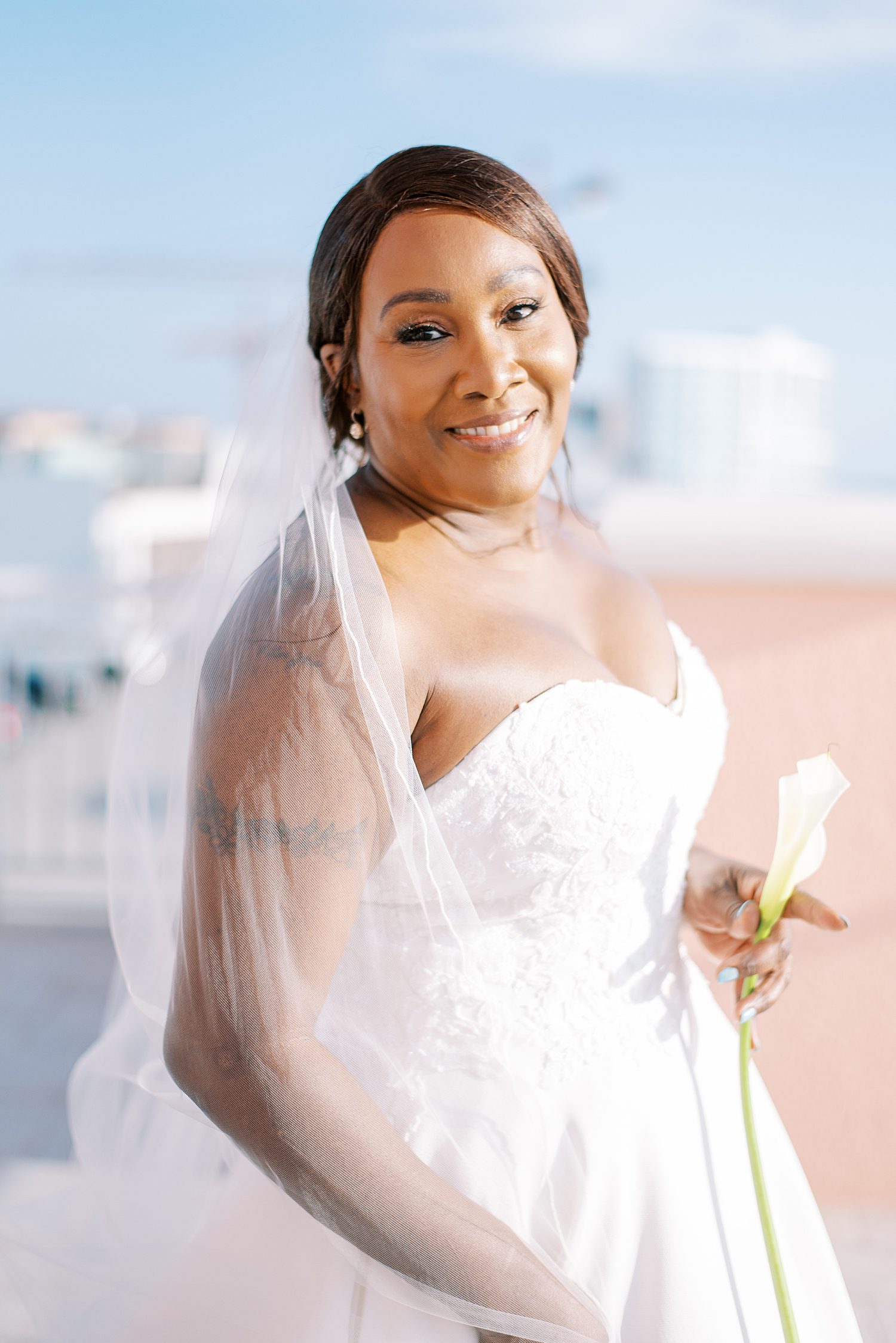 bride poses in strapless wedding gown with veil around her shoulders 