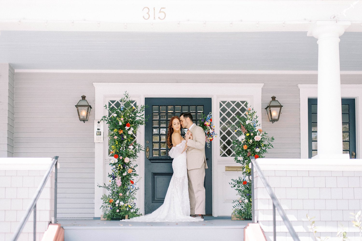 bride and groom hug on front porch between floral displays in Tampa FL at The Orlo