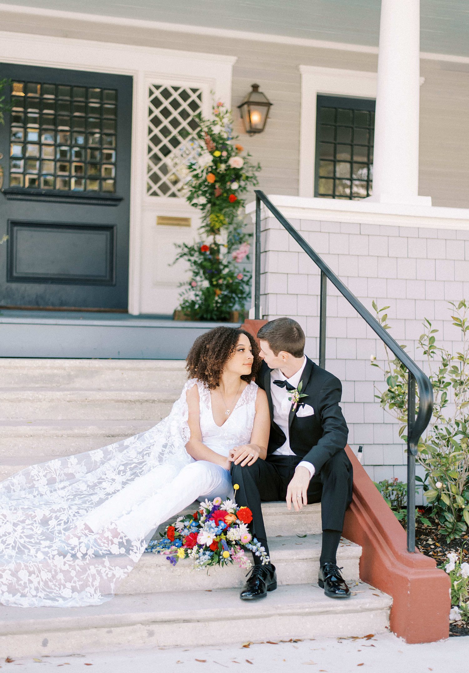 bride and groom sit on steps outside The Orlo leaning together 