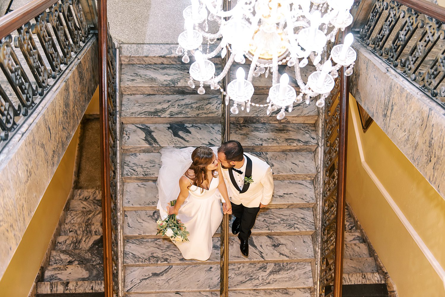 bride and groom kiss on marble staircase inside Centro Asturiano de Tampa