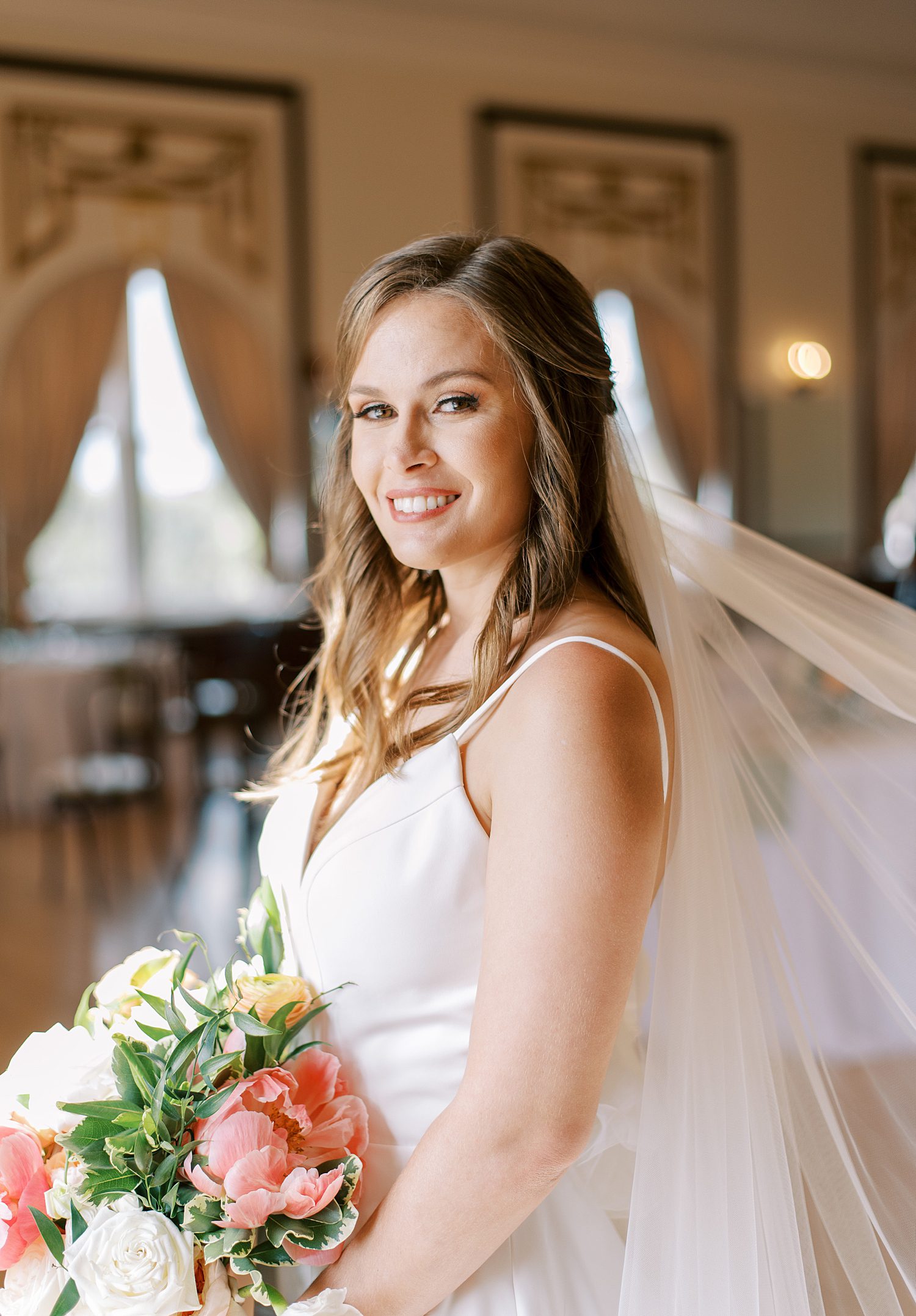 bride smiles inside Centro Asturiano de Tampa with veil behind her 