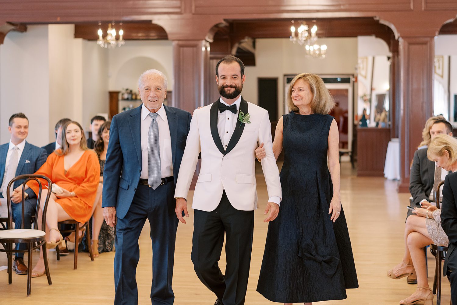 groom holds parents' hands walking down aisle at Centro Asturiano de Tampa