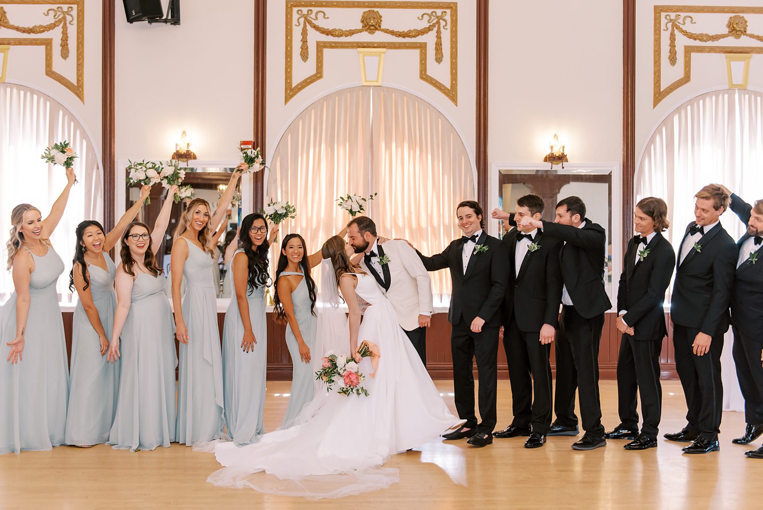 newlyweds kiss with wedding party around them at Centro Asturiano de Tampa