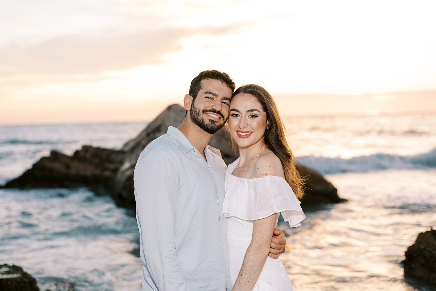 man and woman hug in front of ocean with rocks at Fort De Soto beach