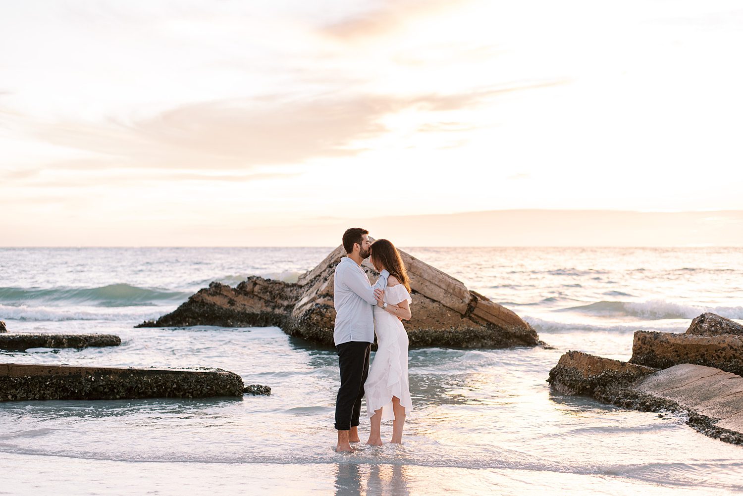 groom kisses bride's forehead during sunset Fort De Soto beach engagement session