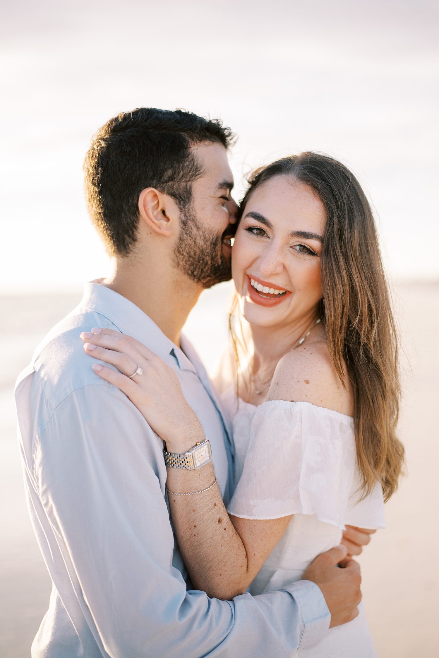 man kisses woman's cheek on beach at sunset during Tampa FL engagement photos