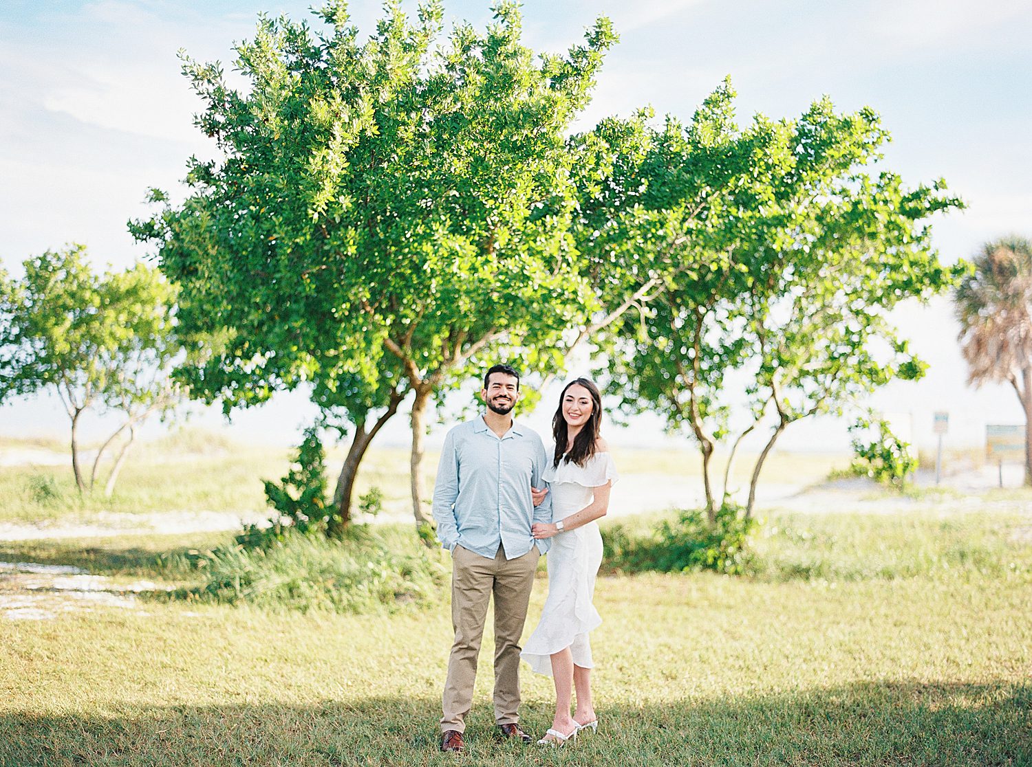 engaged couple hugs in front of tree on Fort De Soto beach