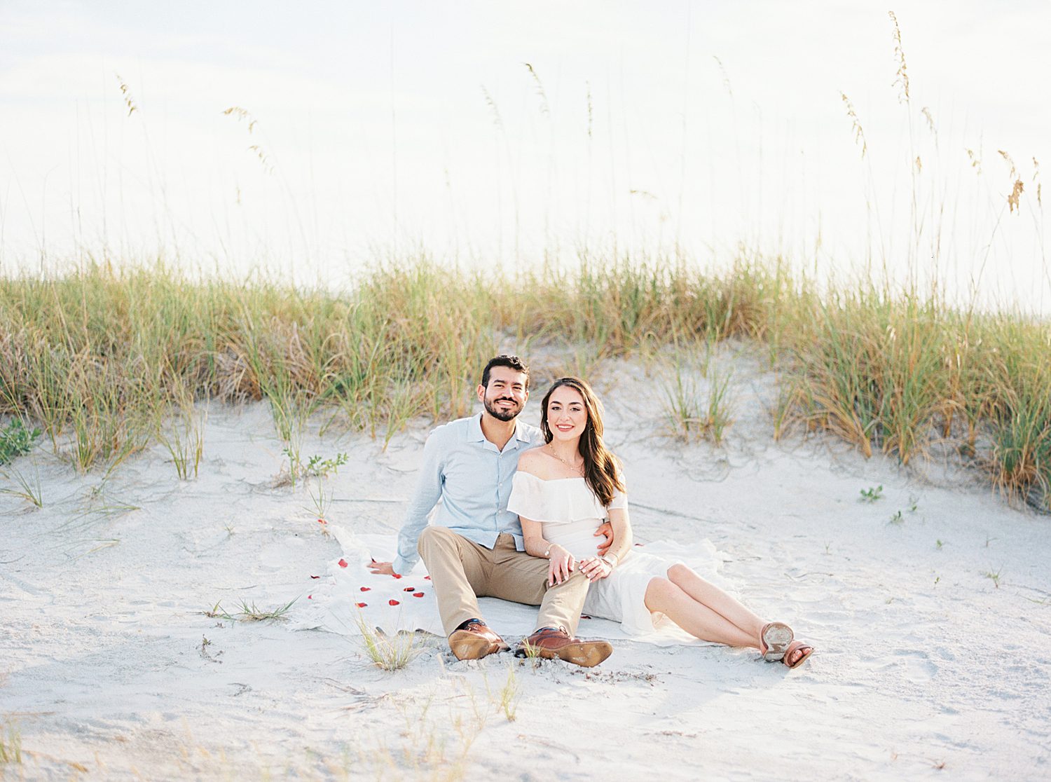 engaged couple sits in front of dune on Fort De Soto beach