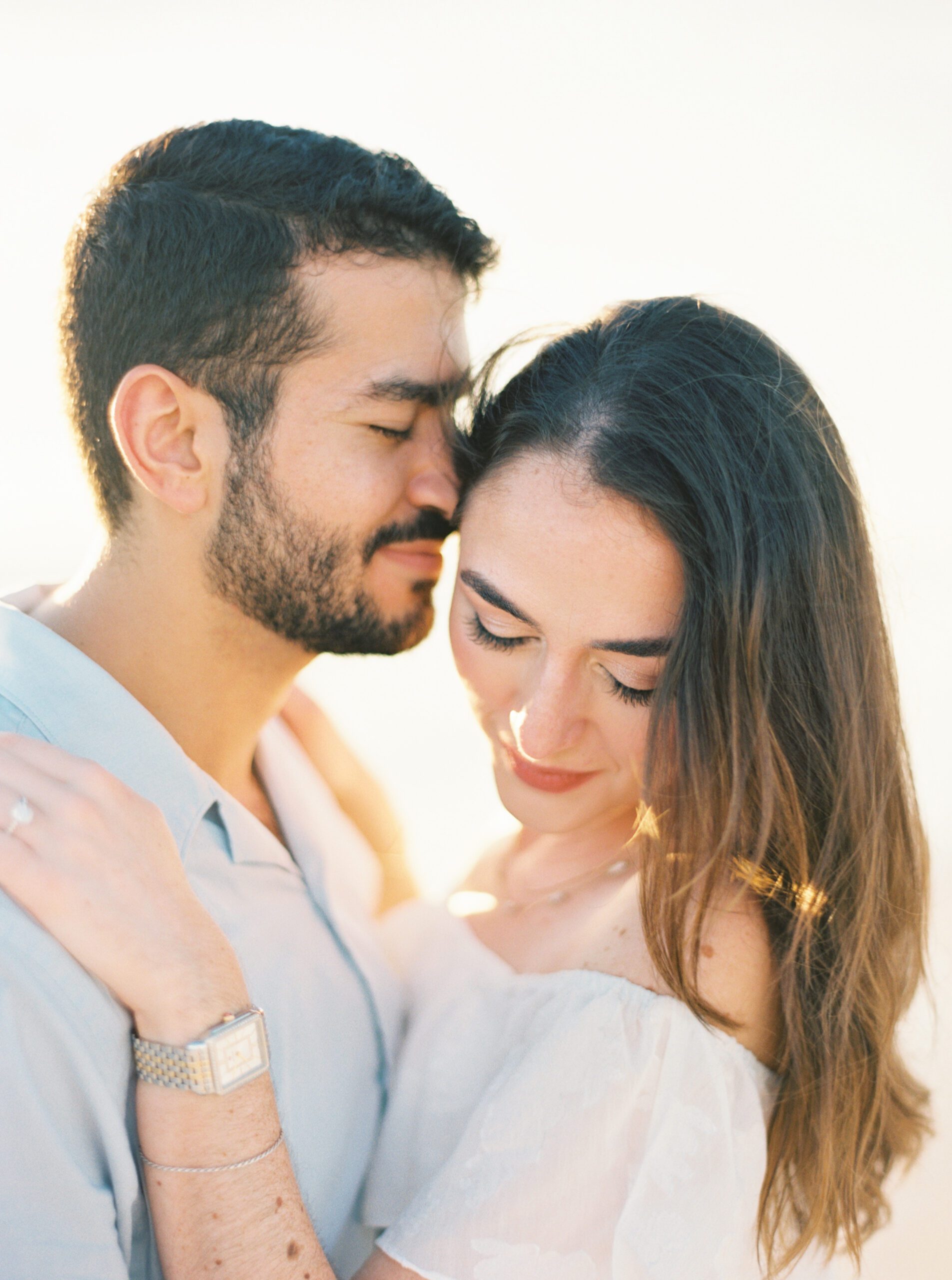 man hugs woman to him nuzzling his cheek in Tampa FL Fort de soto engagement session at the beach