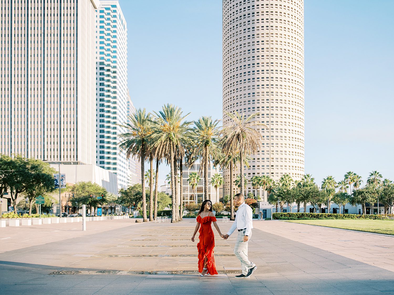 engaged couple holds hands walking in front of palm trees in Curtis Hixon Park