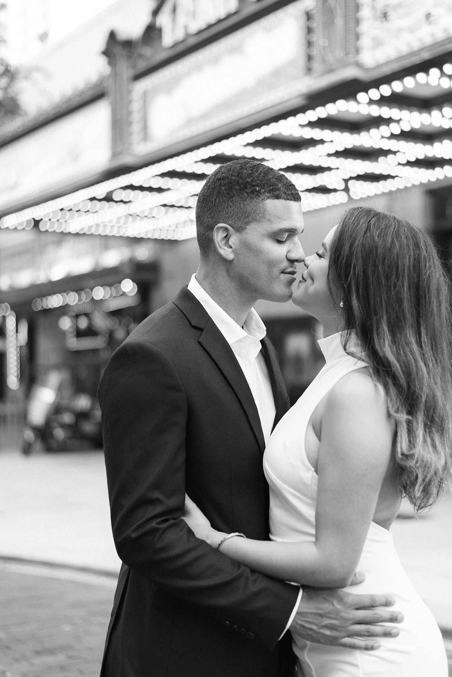 engaged couple leans noses together in front of marquee of Tampa theatre