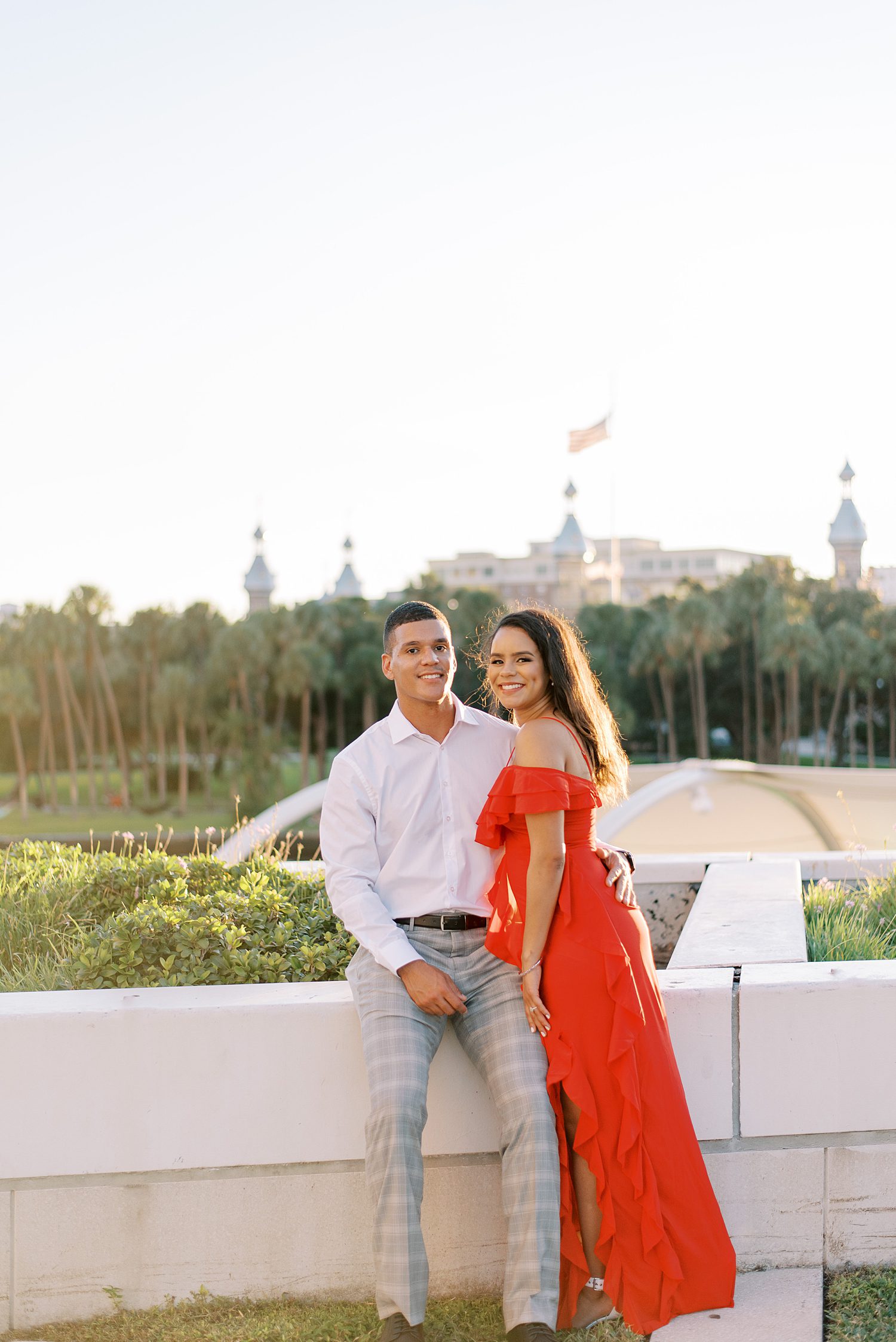 woman in red dress leans against man on white wall in Tampa park