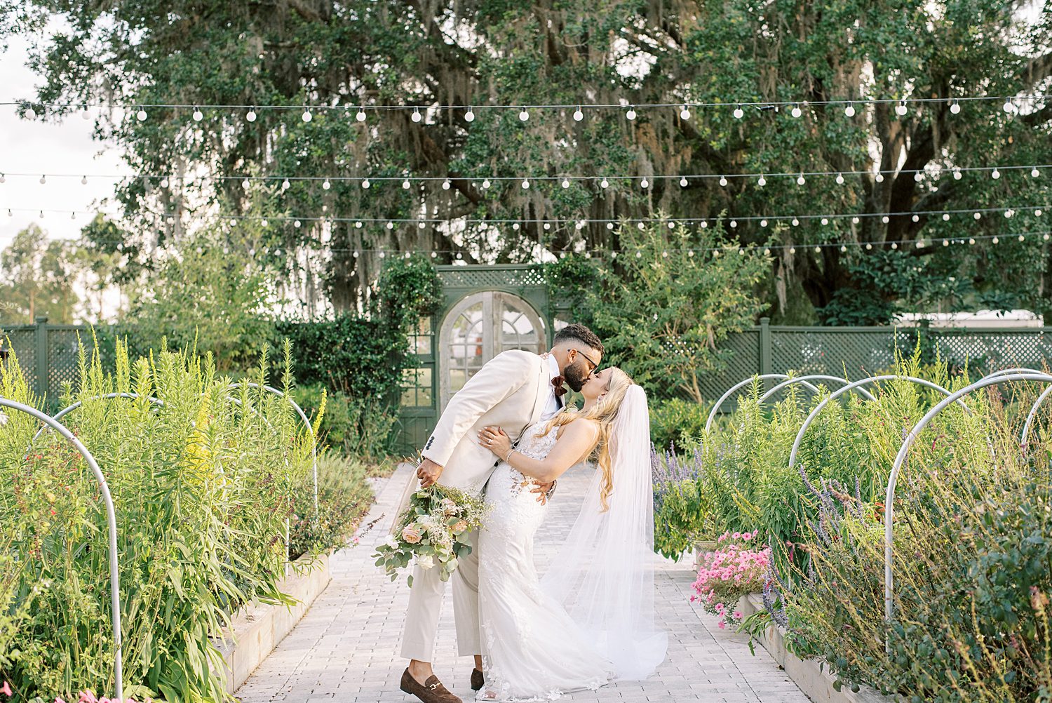 newlyweds kiss between aisle of garden at Mill Pond Estate