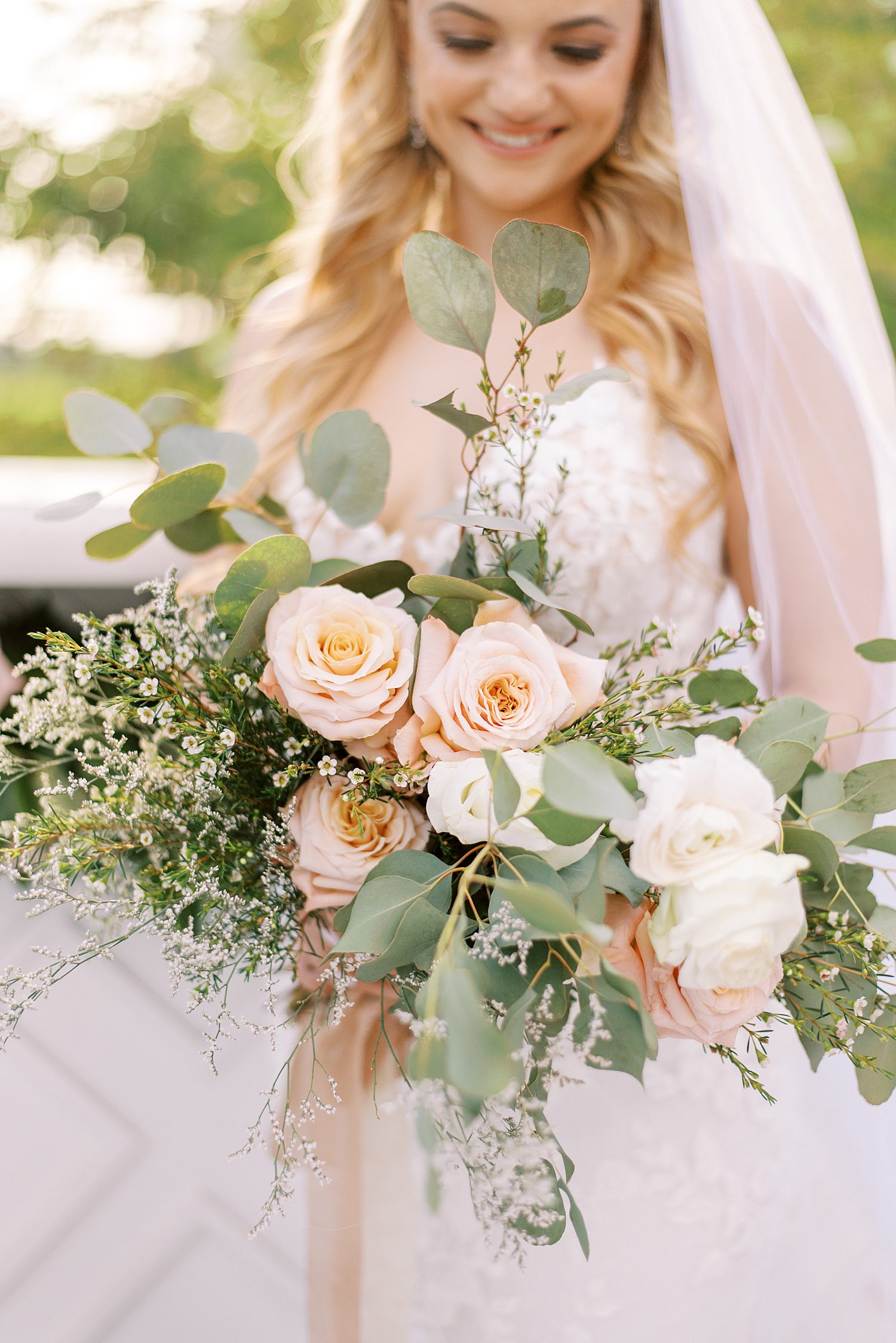 bride holds bouquet of ivory and peach roses 