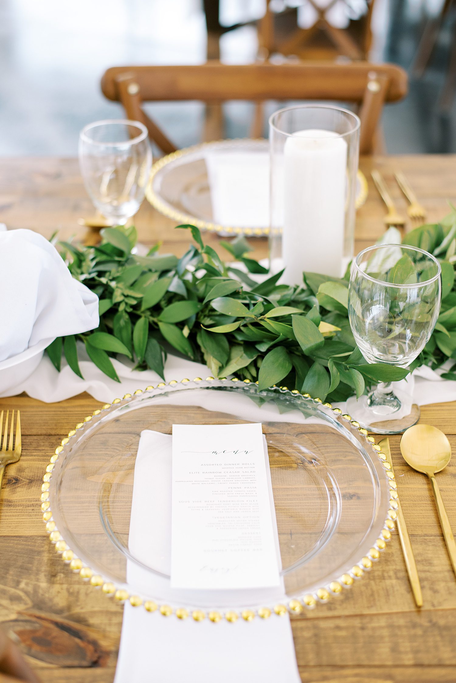 place setting with gold rimmed plates with greenery table runner 