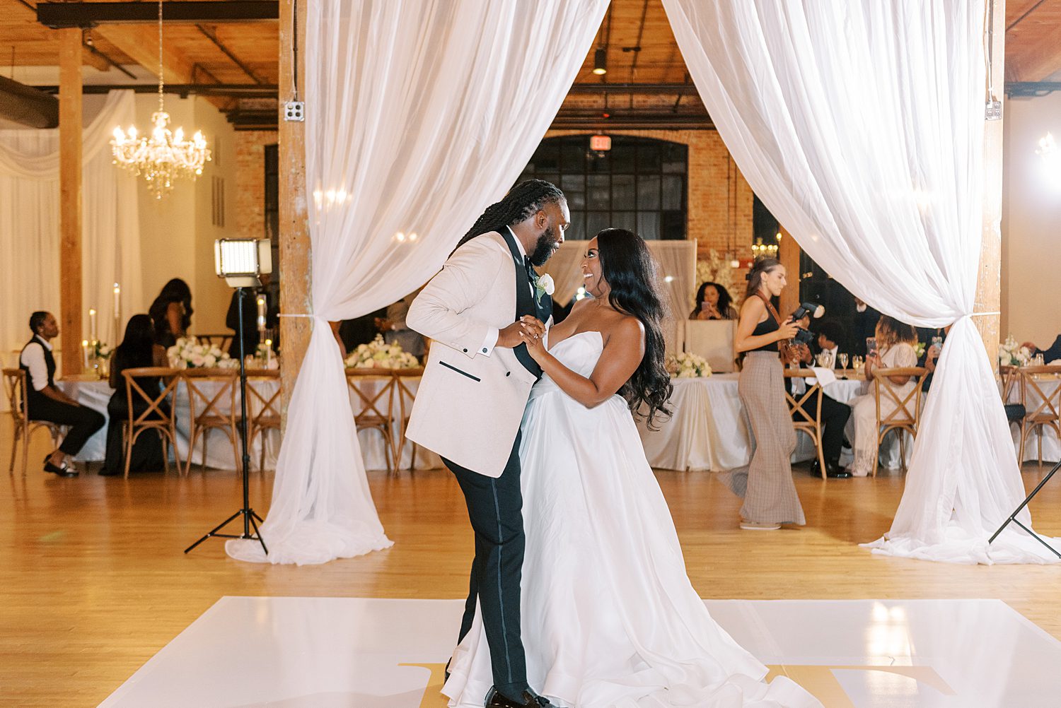 bride and groom dance on dance floor at The Bibb Mill Event Center  with white curtains 