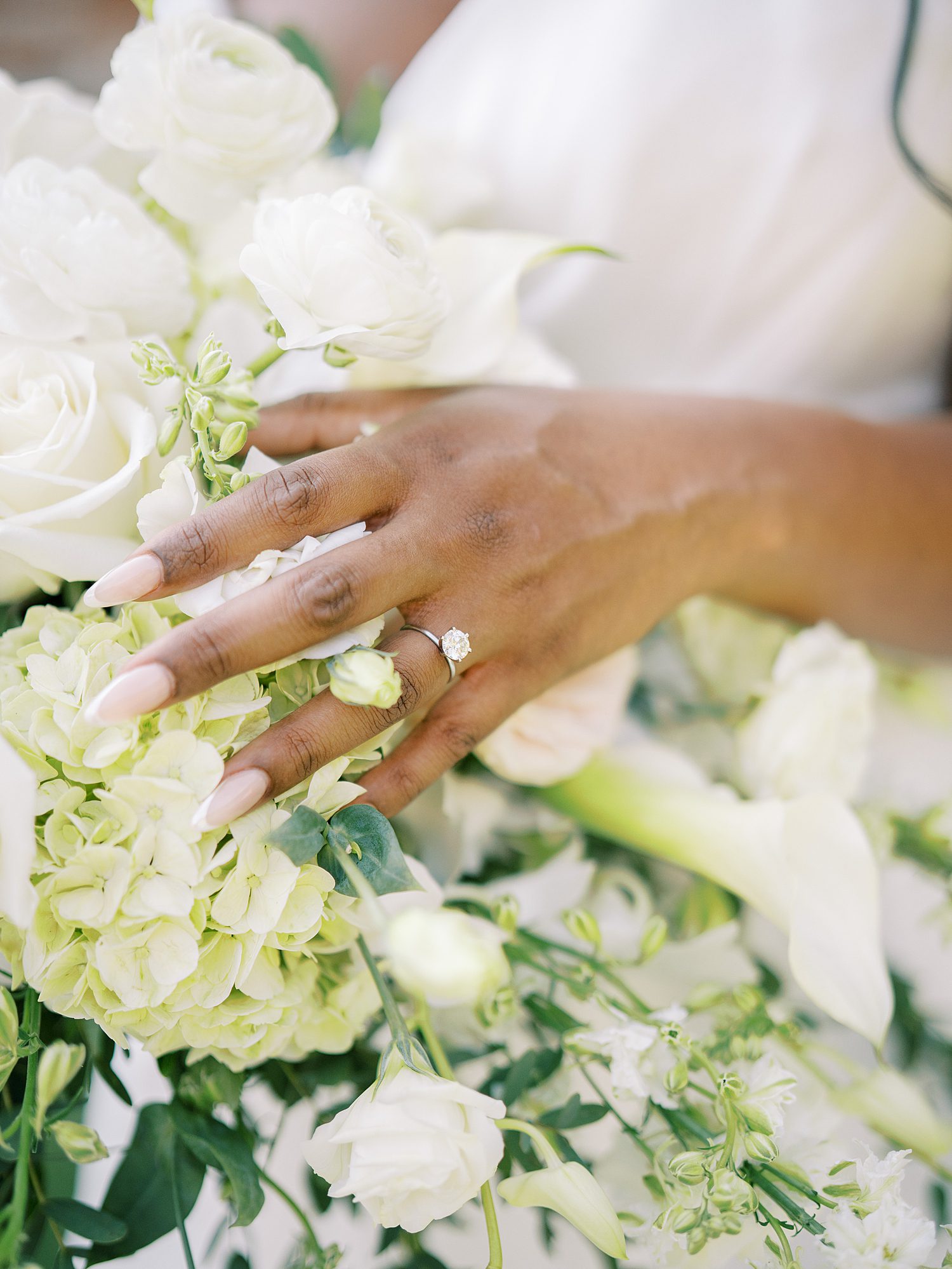 bride shows off wedding ring on white and green flowers for bouquet 