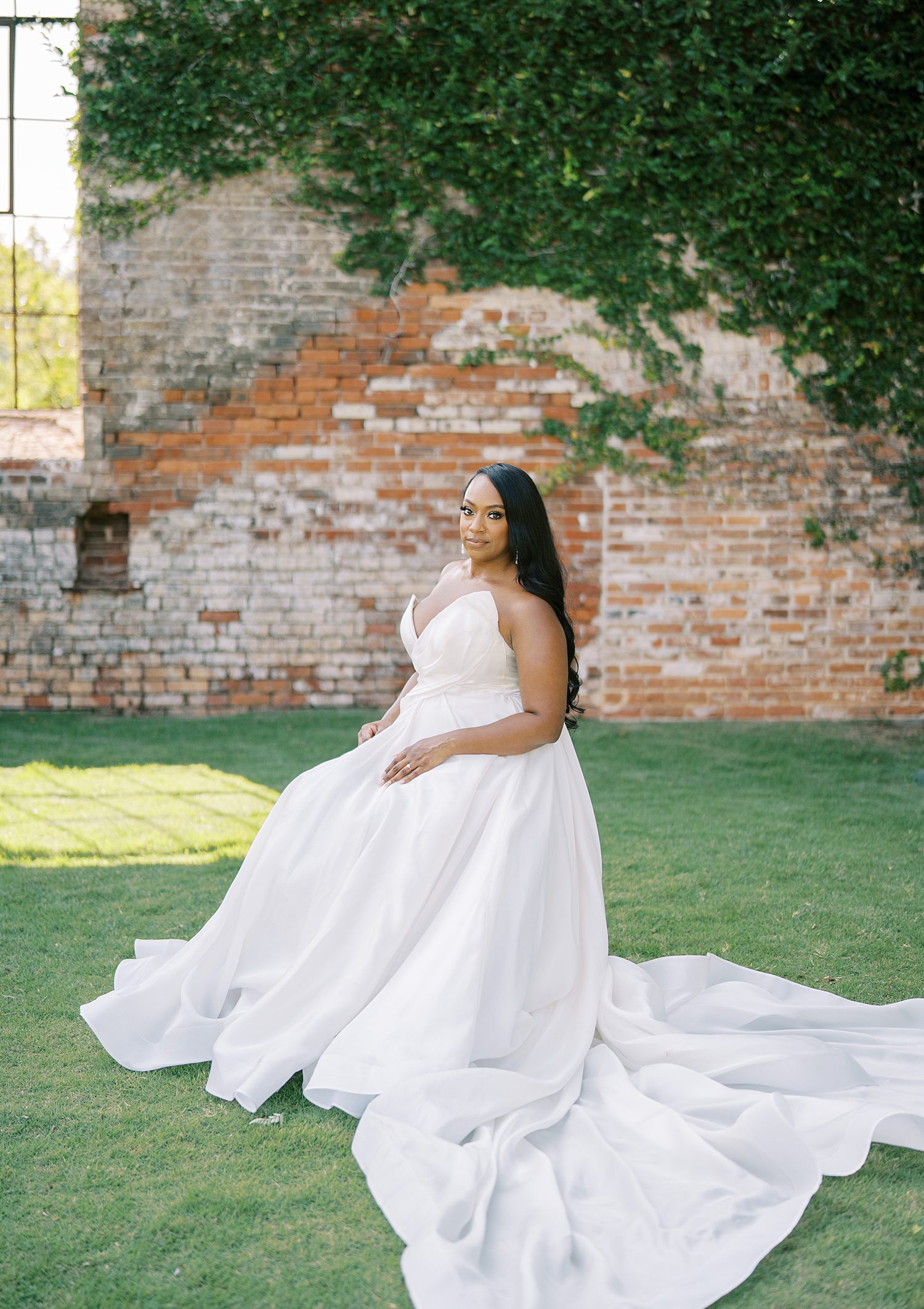 bride turns in strapless wedding gown by brick wall at The Bibb Mill Event Center