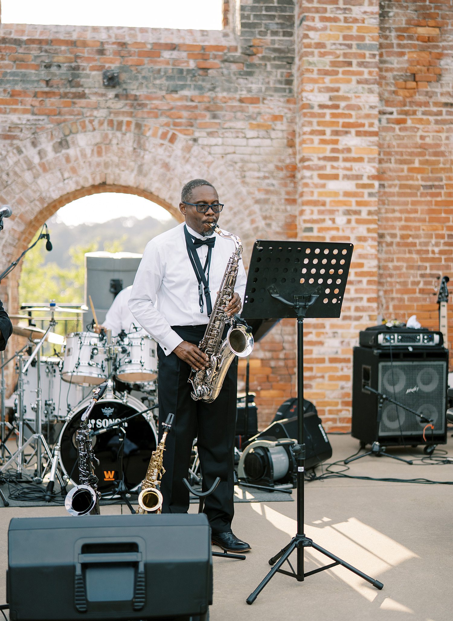 musician in white suit jacket with black lapel with saxophone plays 