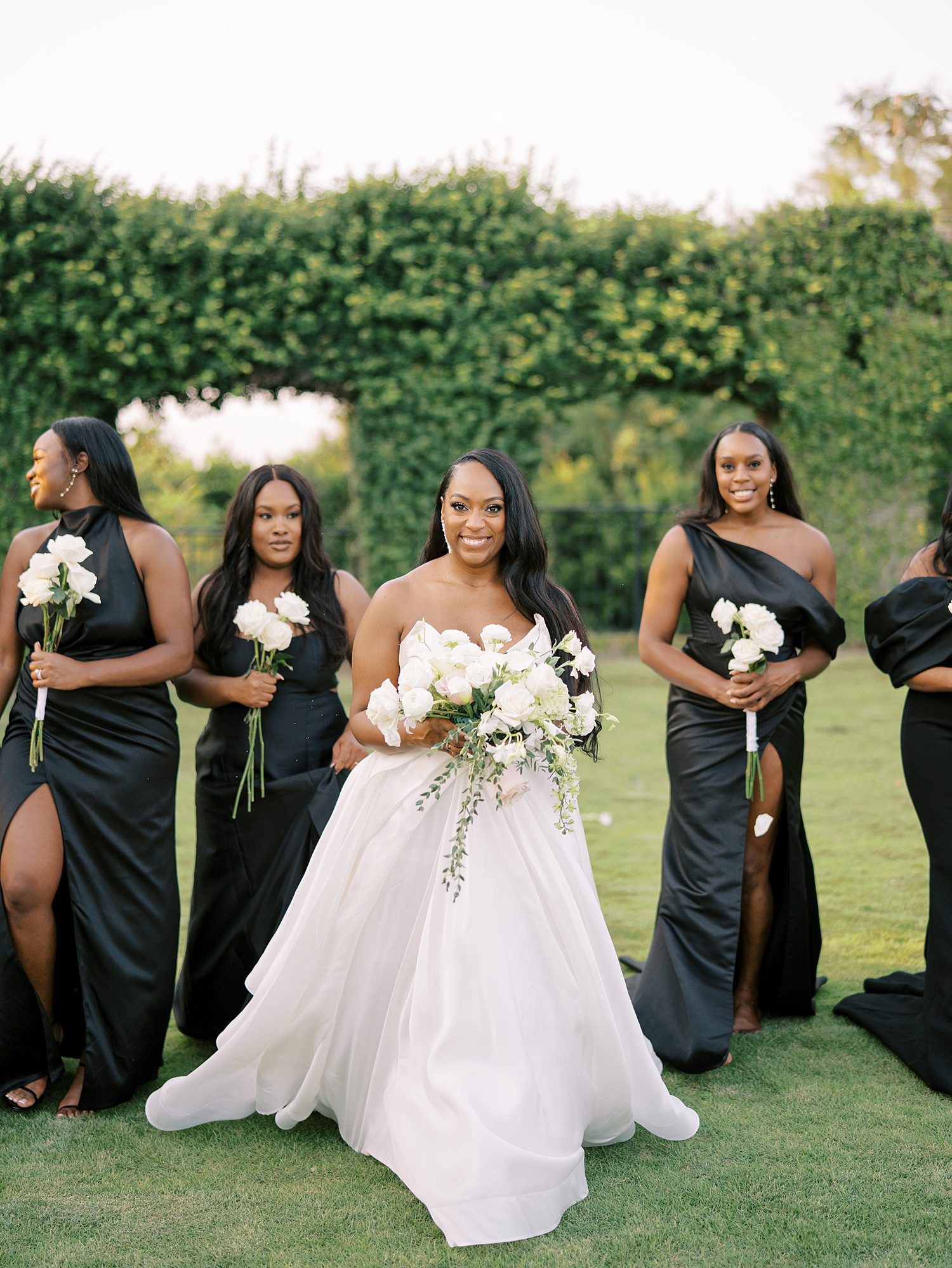 bride poses with bridesmaids in mismatched black gowns 