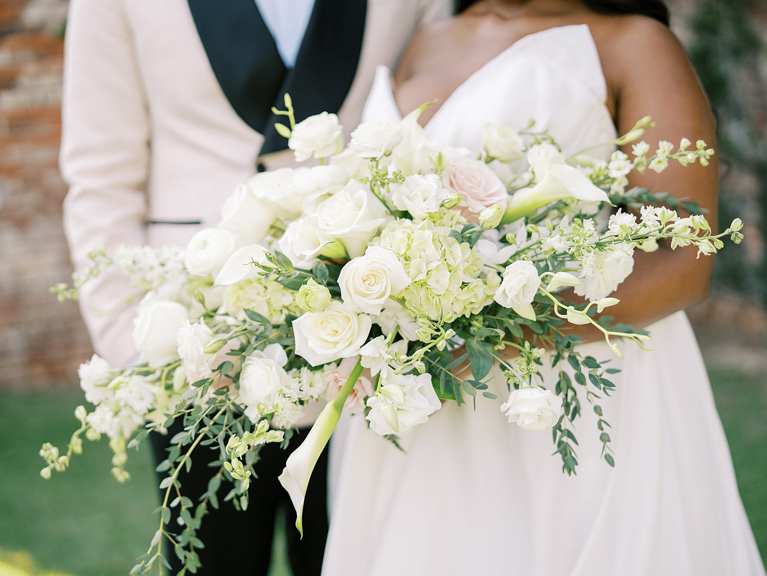bride and groom hug holding bride's bouquet of ivory flowers 