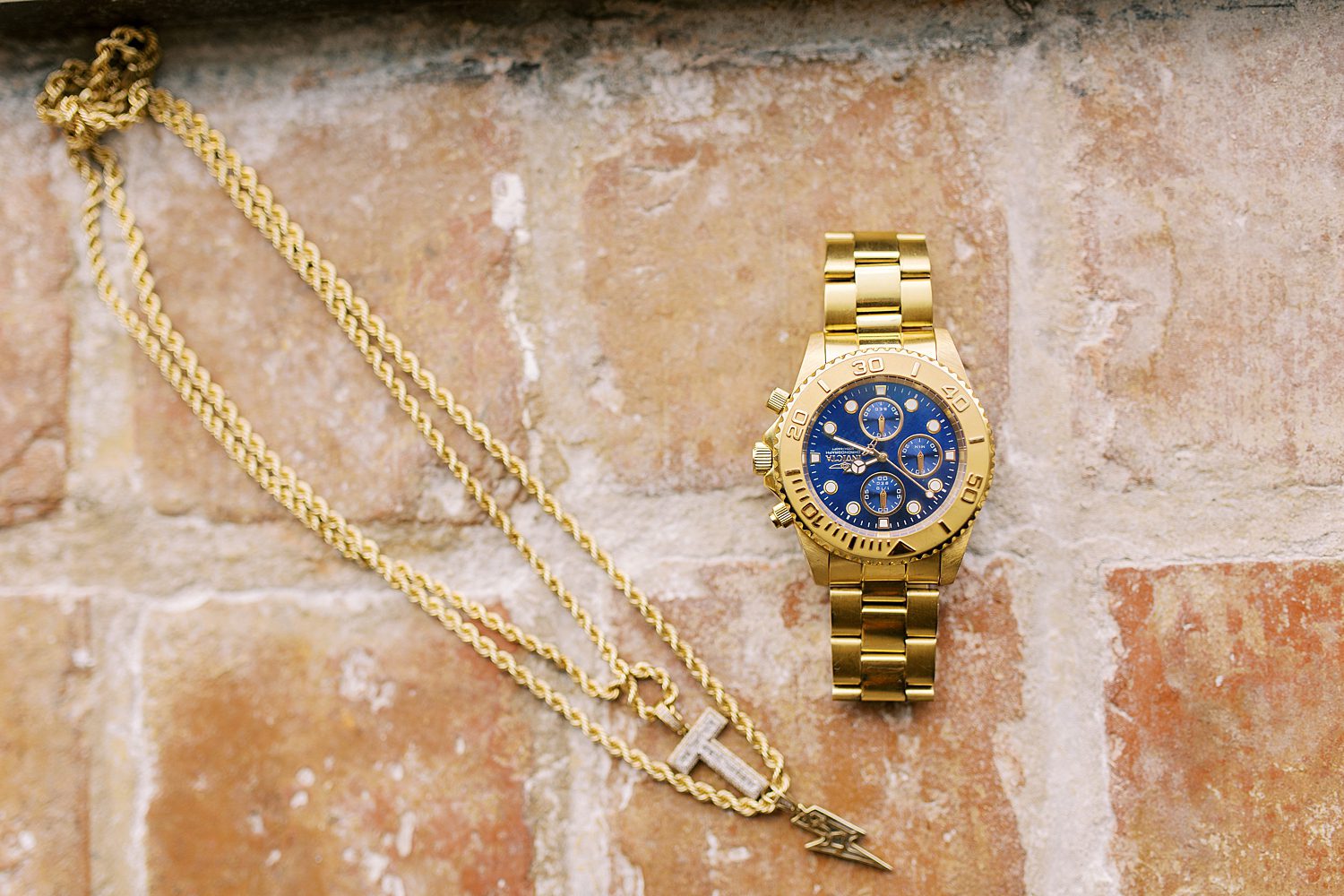 gold watch and necklace on brick 