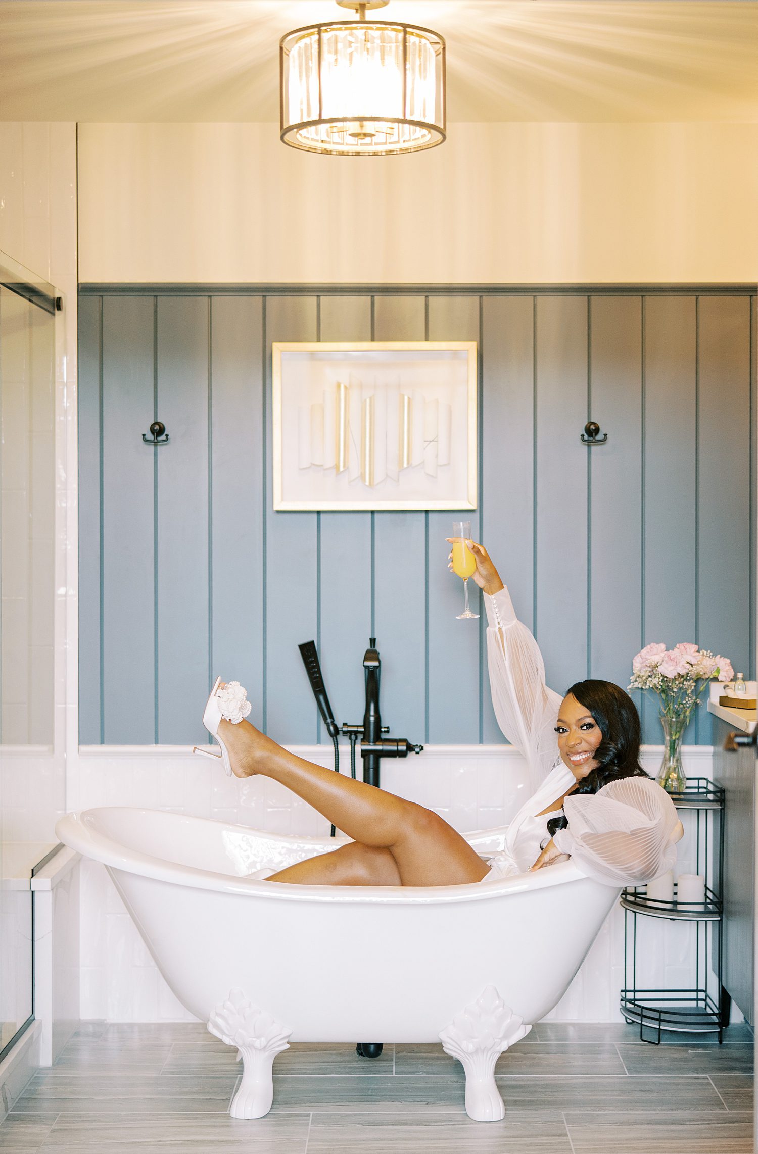 bride sits in tub holding up mimosa before Georgia wedding day