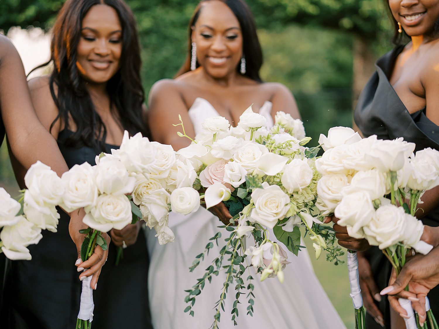 bride and bridesmaid in black gowns hold white flowers at The Bibb Mill Event Center