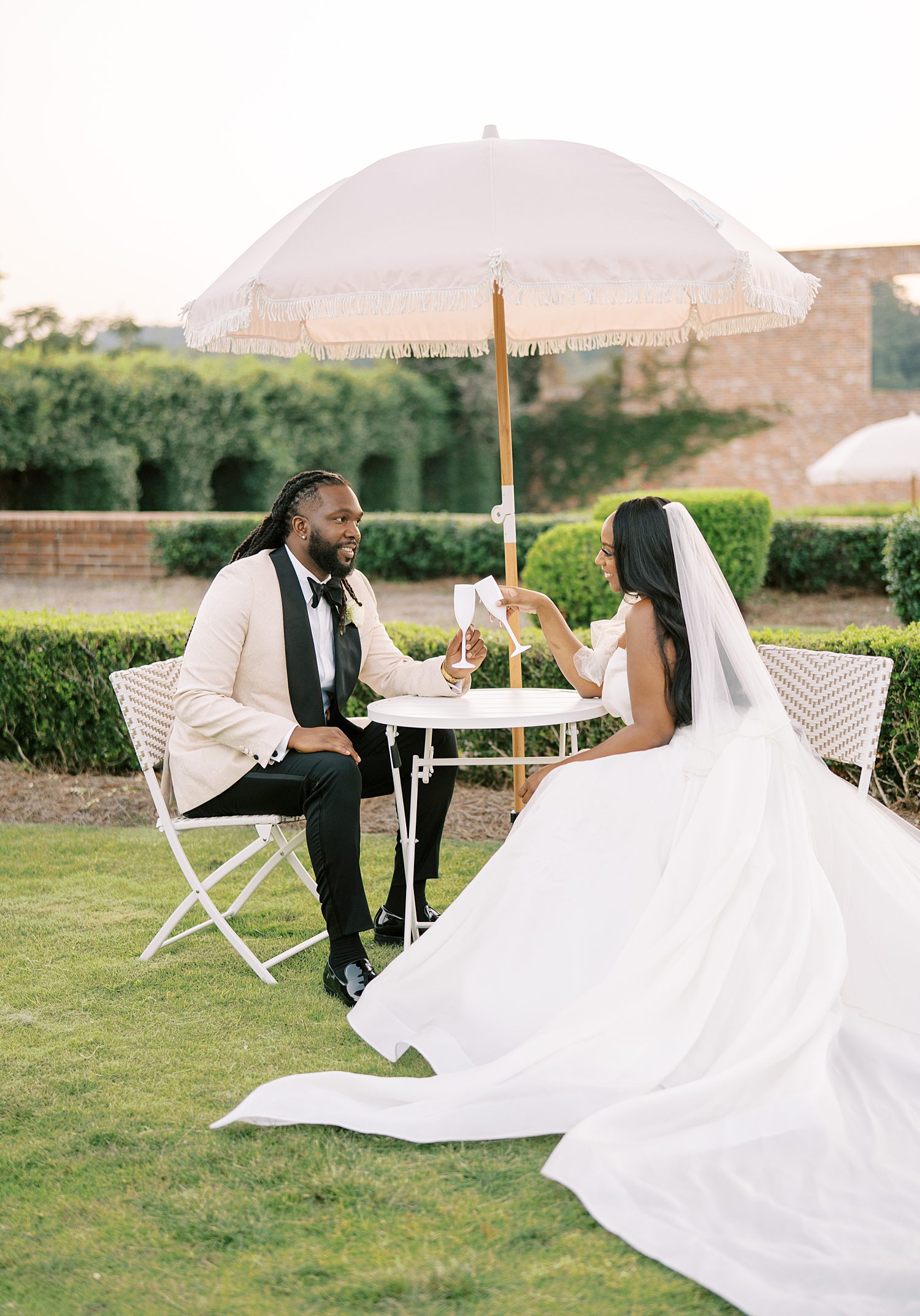 bride and groom toast champagne at small table under white umbrella 