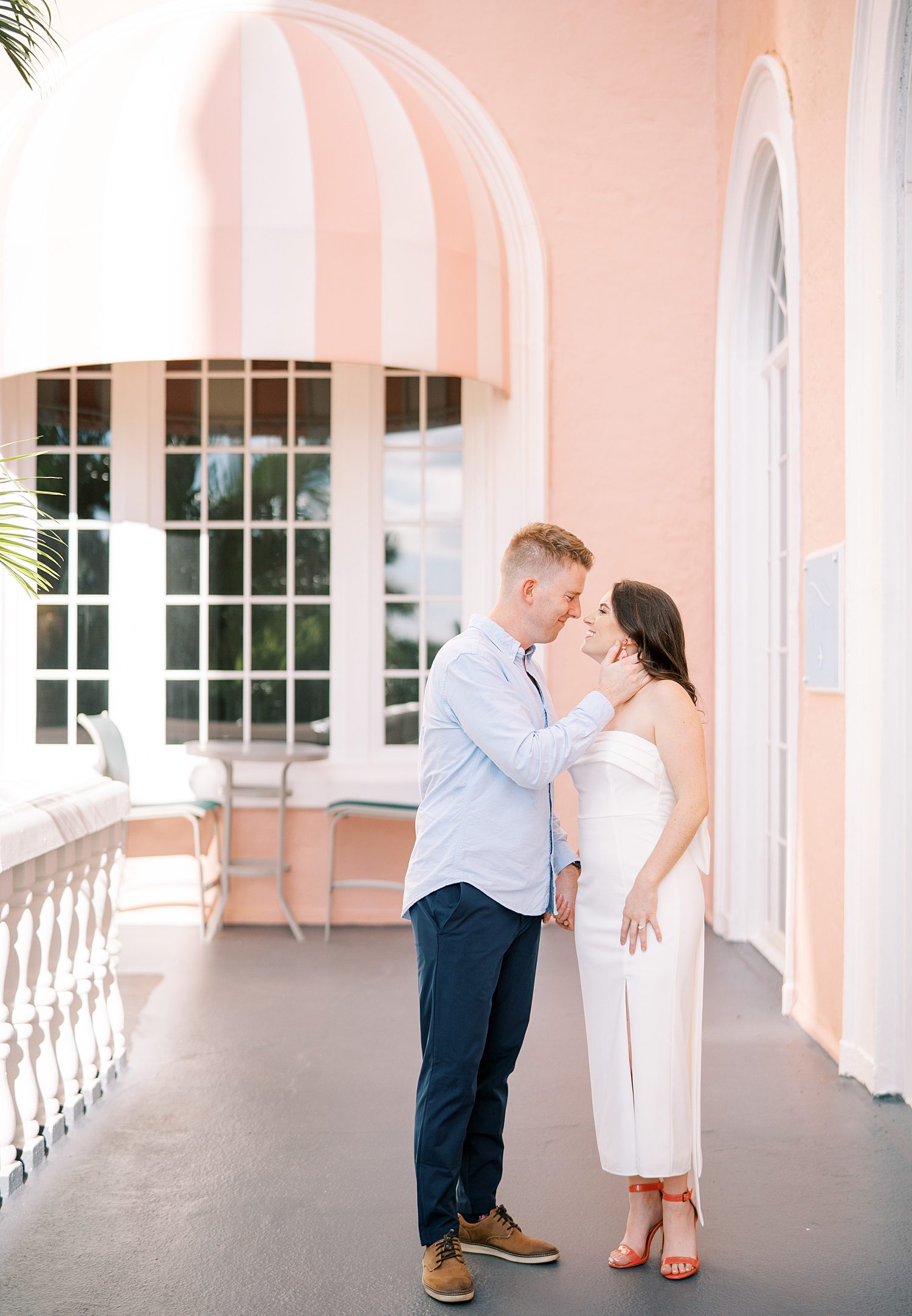 man holds woman's chin in front of pink walls of the Don Cesar Hotel