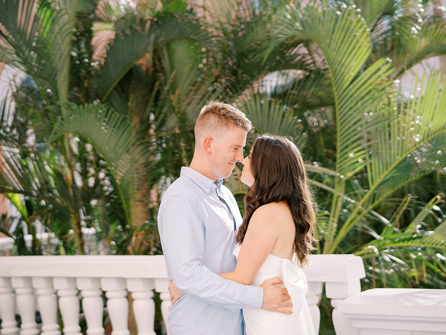 engaged couple hugs in front of green leaves on balcony at the Don Cesar Hotel